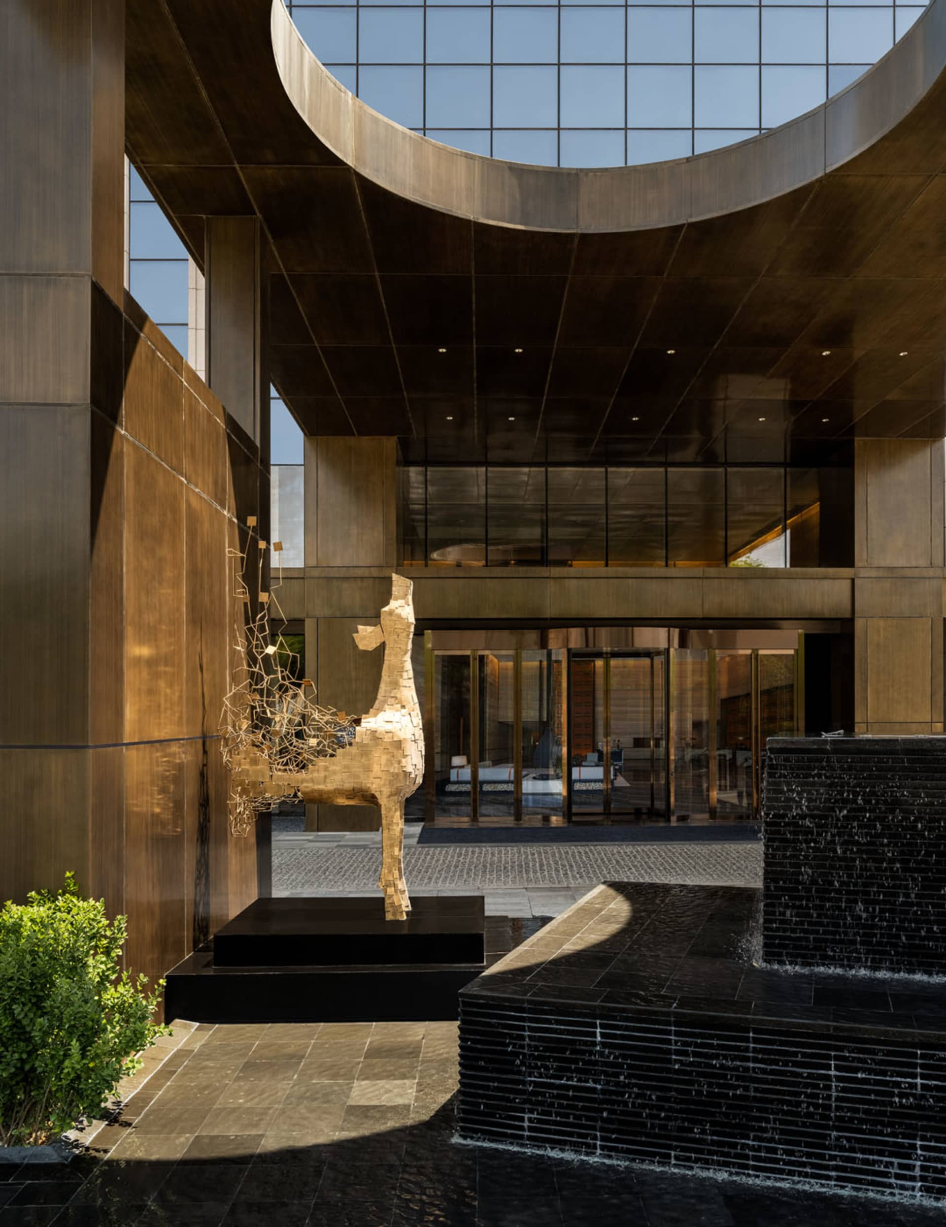 現代大廳展示金屬與玻璃建築雕塑，以及一座石材噴泉。