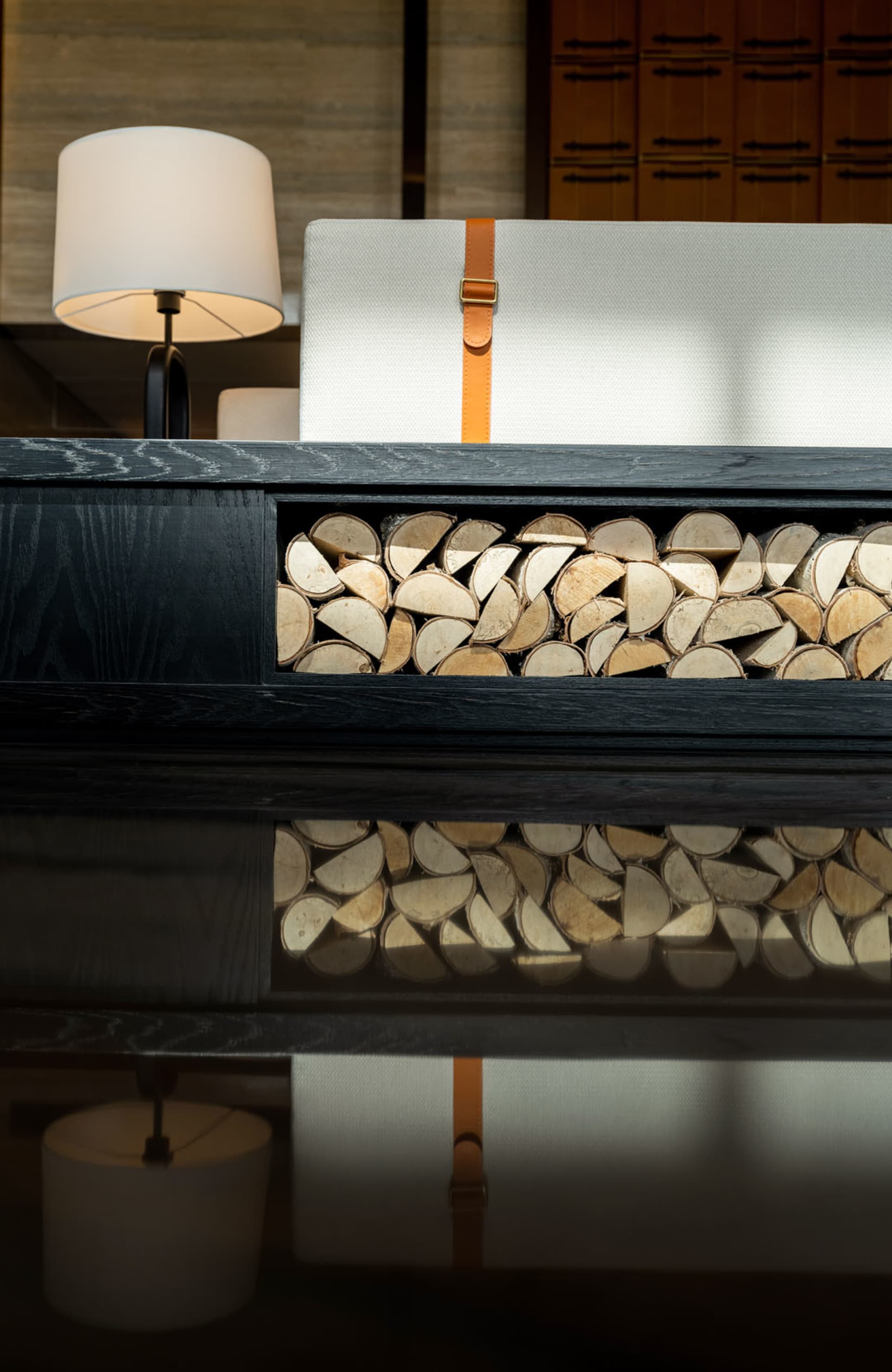 A black chest with a wooden storage compartment, featuring a lamp and a white cushion.