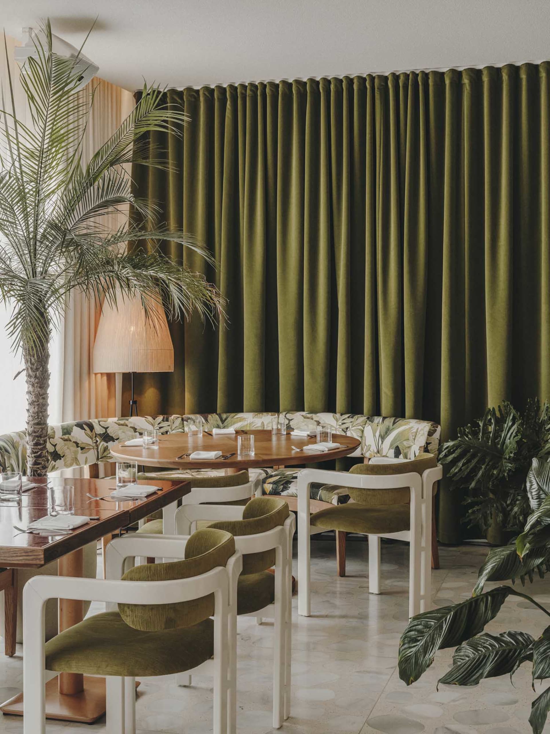 A modern restaurant interior with green globes and tropical plants.