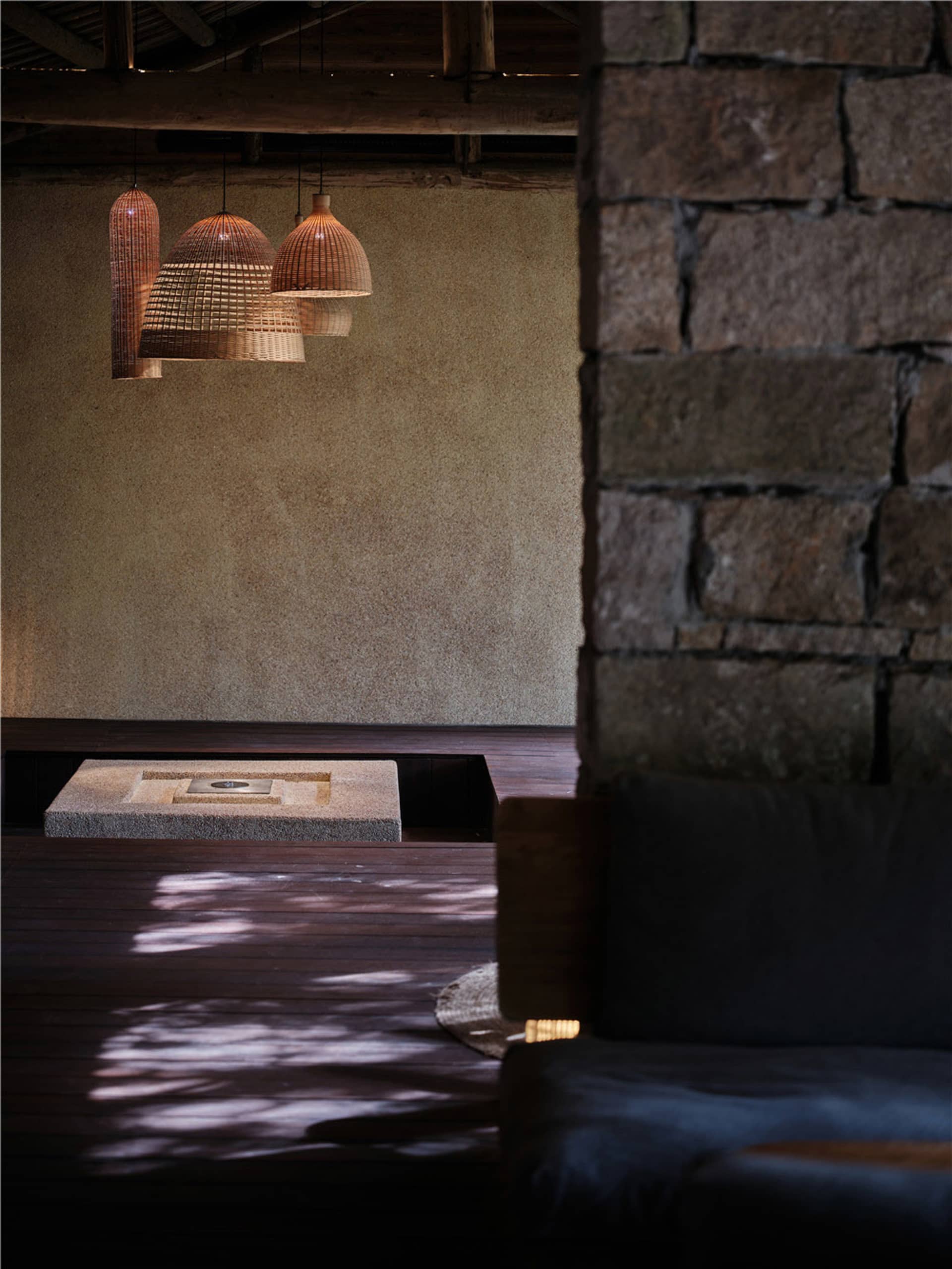 Modern minimalist living room featuring wood flooring, stone walls, and metal accents.