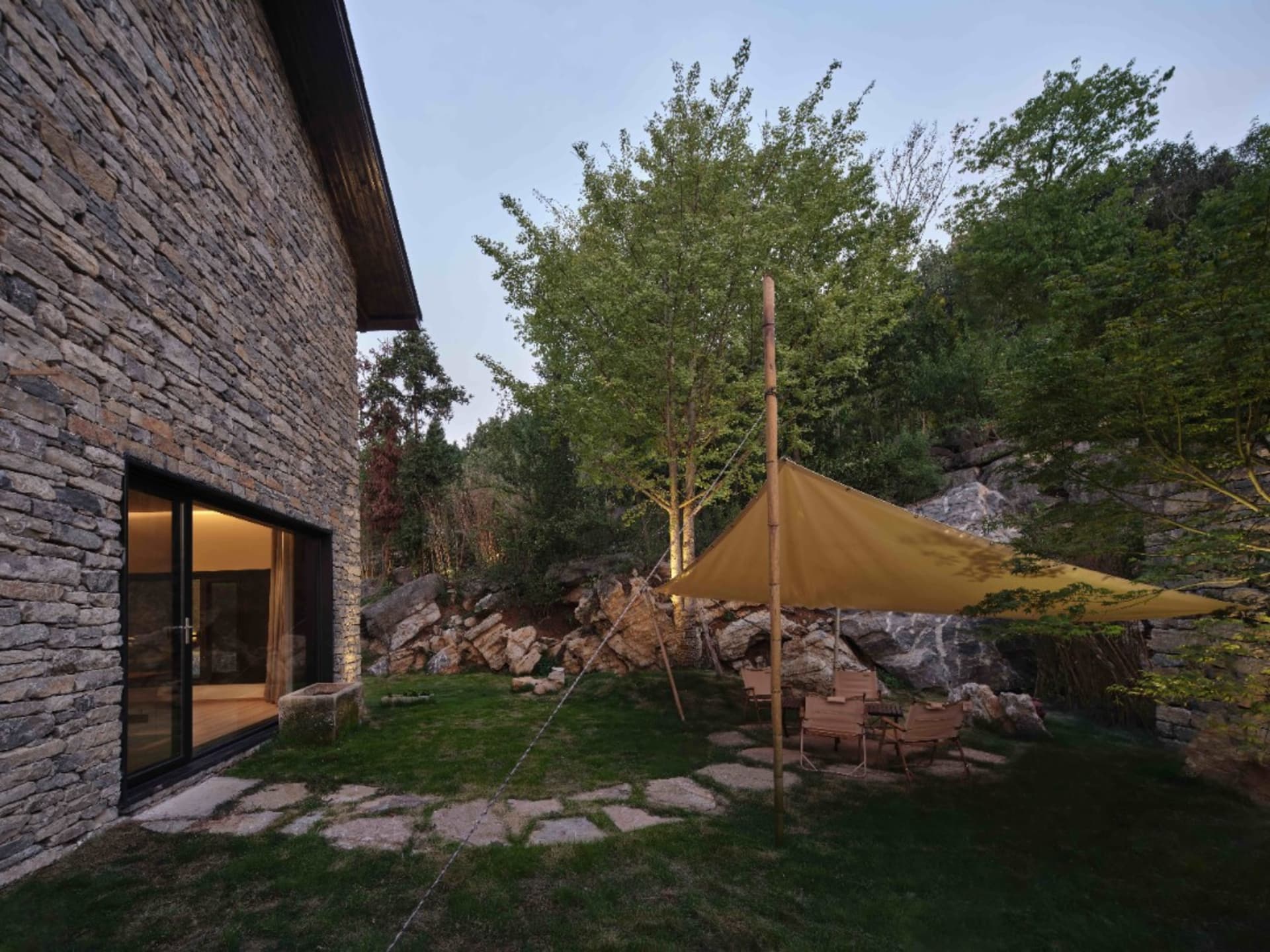 Outdoor patio with modern furniture, rock walls, and a tent setup
