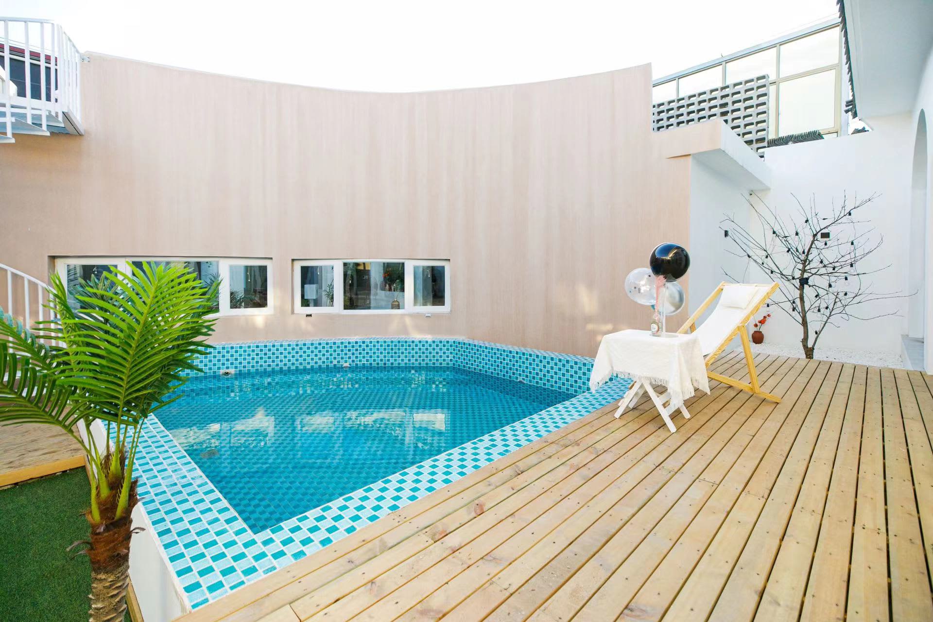 A modern residential space featuring a pool with blue-tiled walls and a wooden deck.