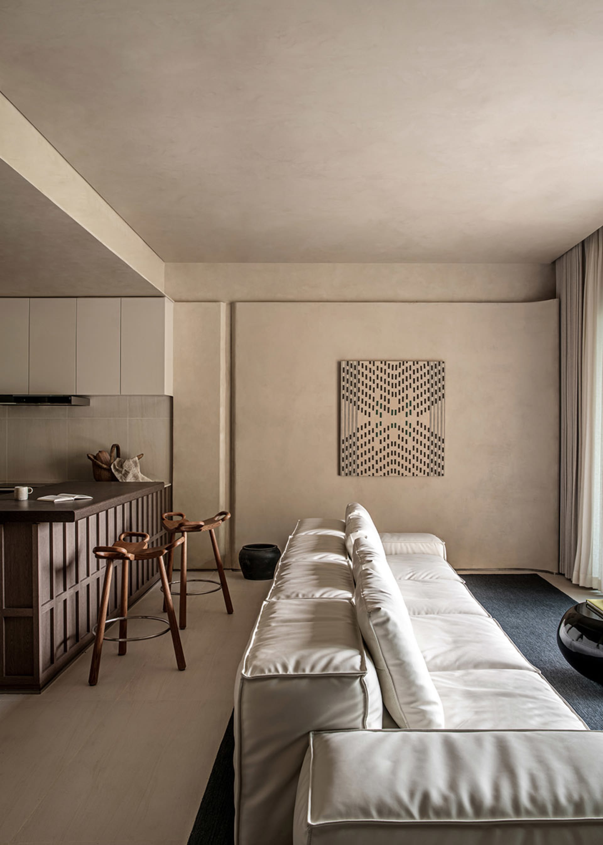 Modern living room with white sofa and geometric pattern on wall.