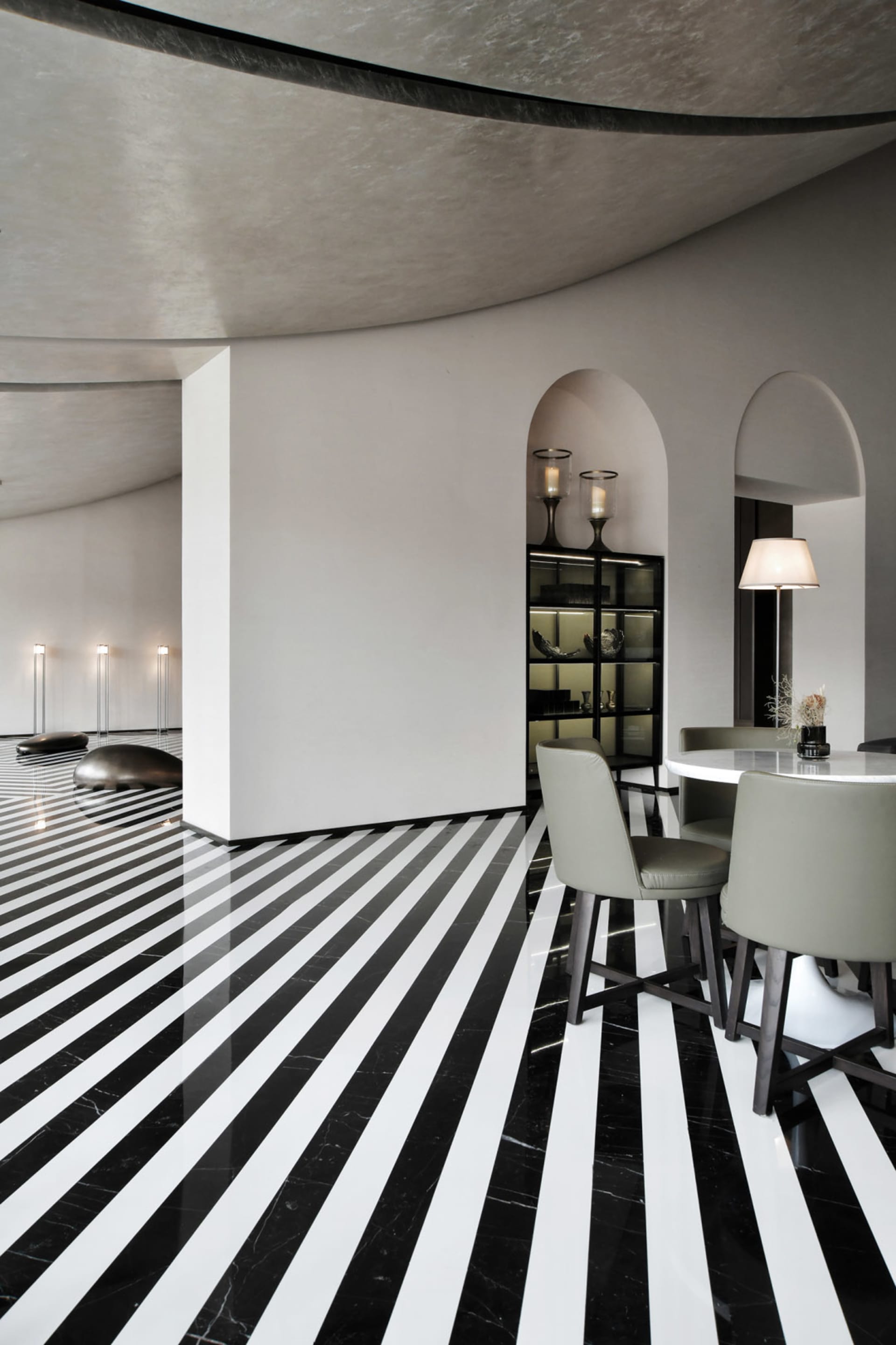 A modern dining room with concrete walls, marble flooring, and a round table with chairs.