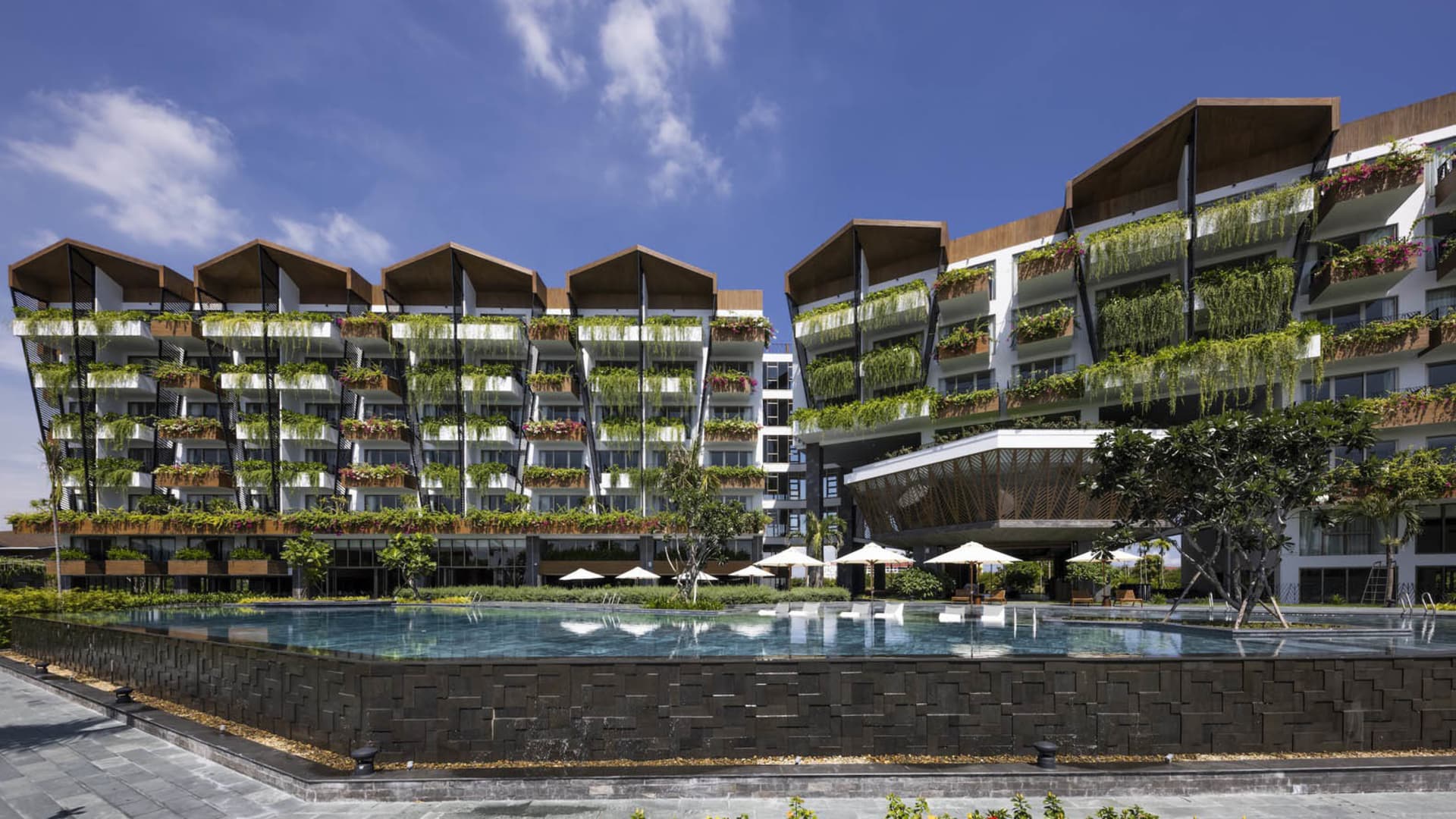 Modern residential building with metal accents and greenery balconies