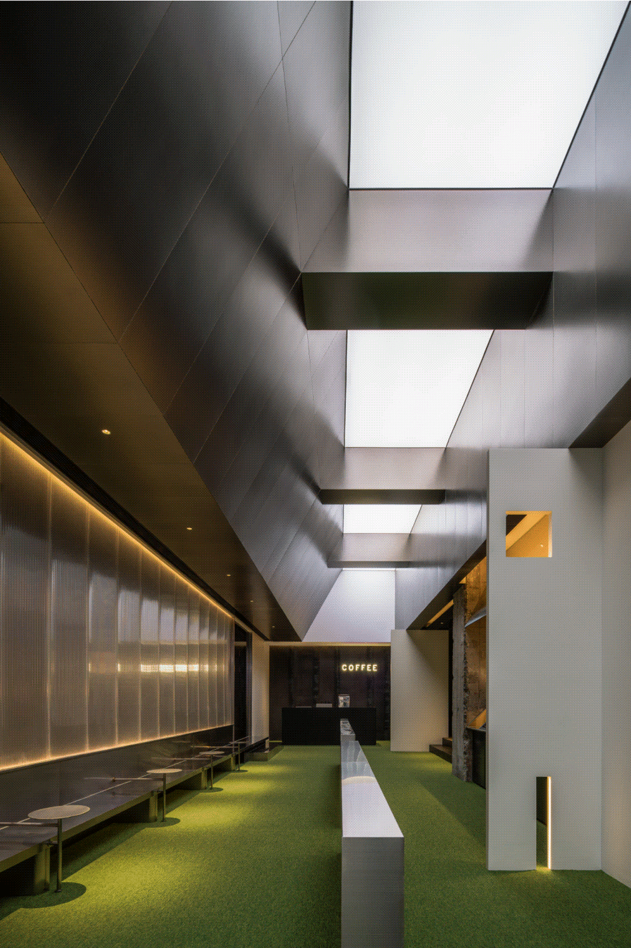 Modern office space with concrete walls, glass partitions, and green carpeted flooring.