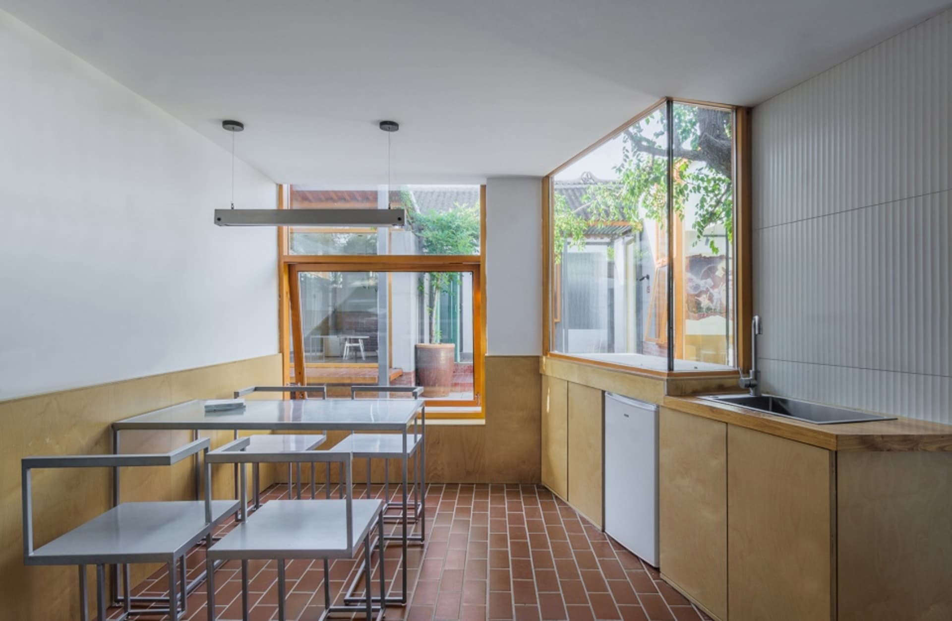 Minimalist kitchen featuring wood and metal accents, with large windows and a white refrigerator.