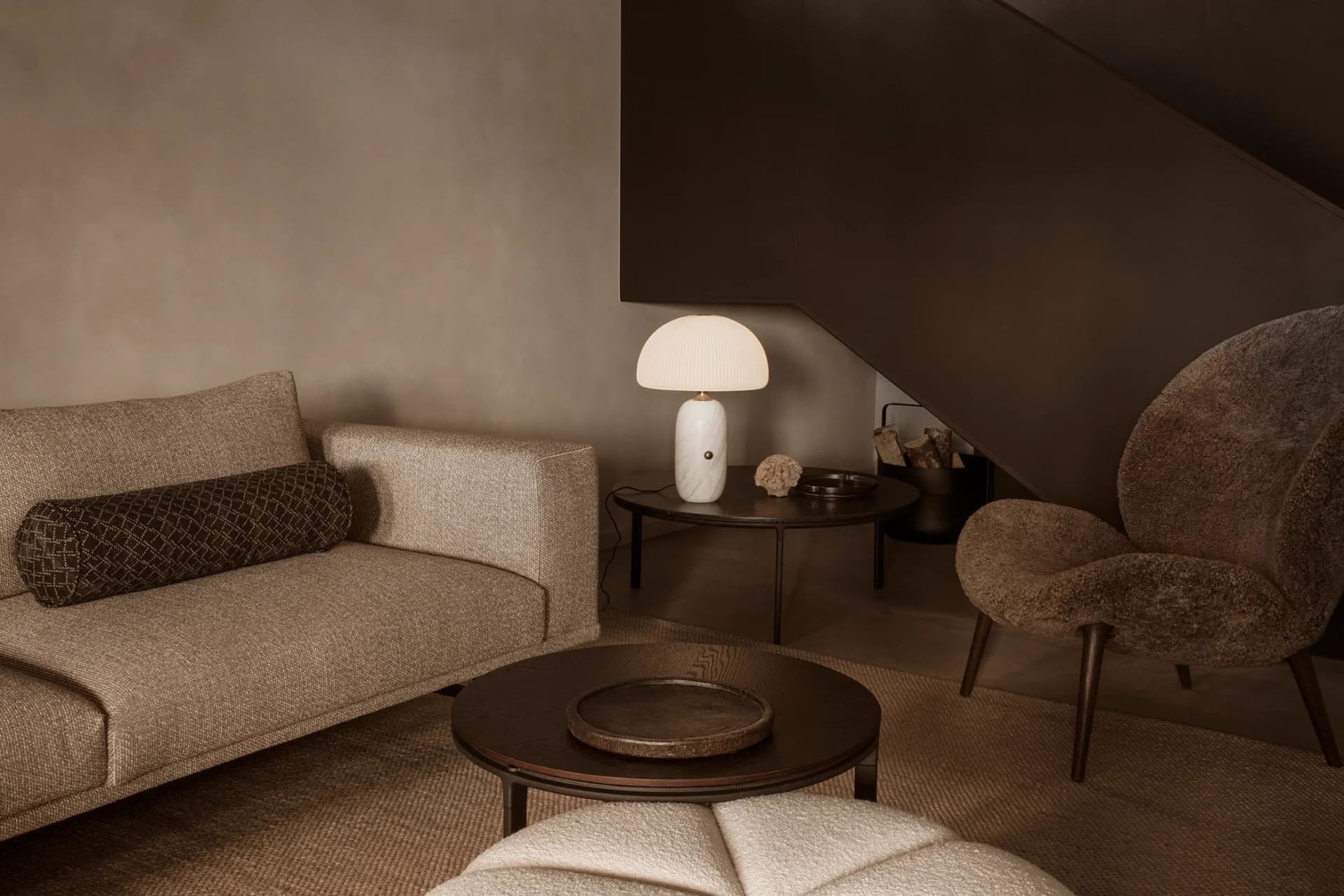A modern living room featuring a couch, armchair, coffee table, and a marble table lamp.