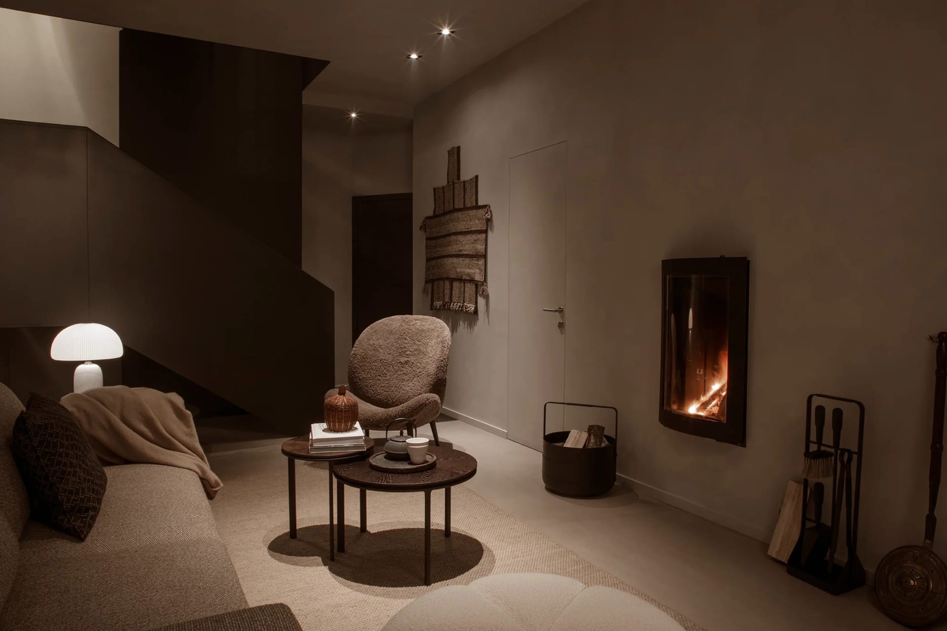 A cozy, modern residential space featuring concrete walls and a plush, comfortable seating area with a fireplace.