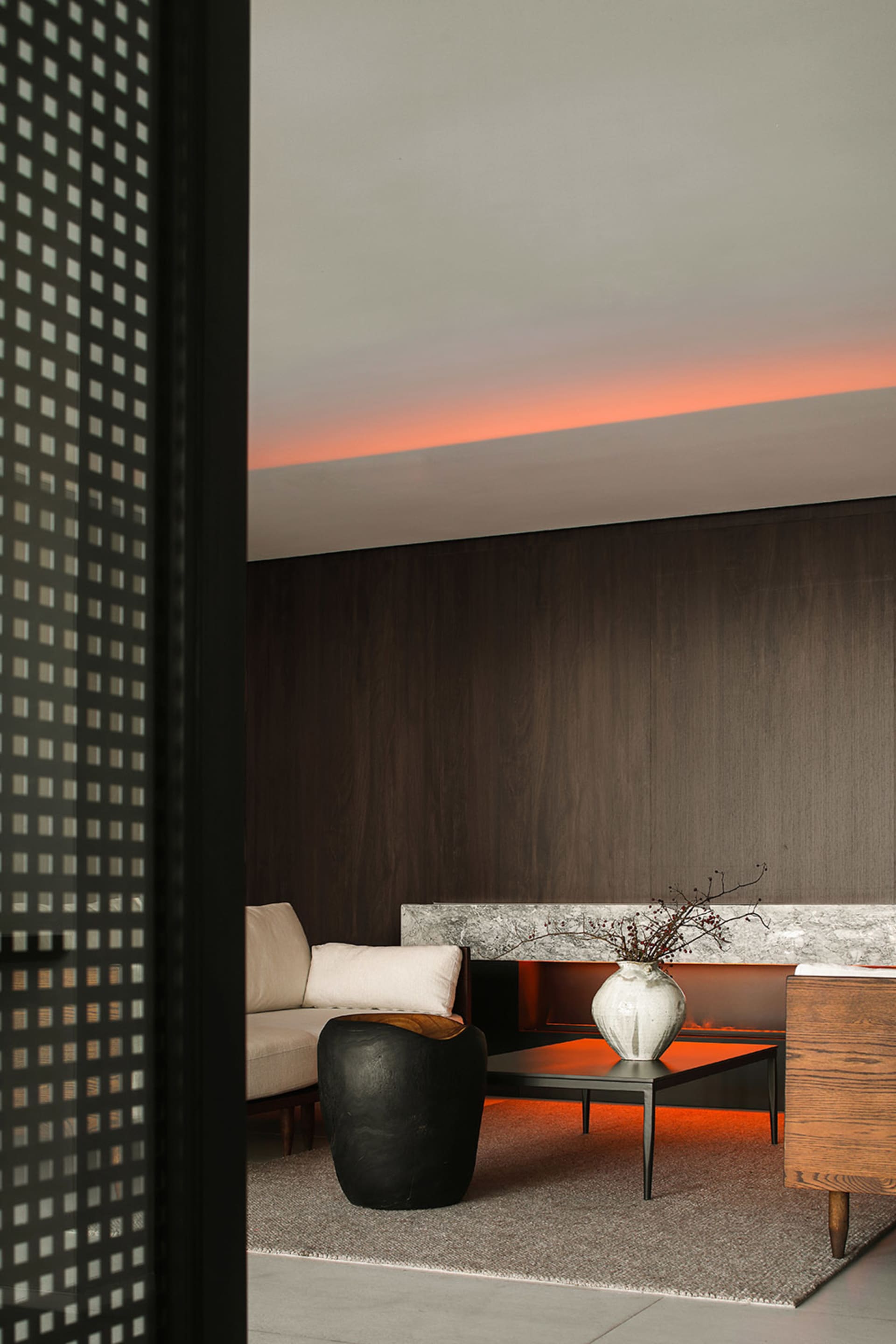Modern living room with concrete walls and furniture, featuring a black sculptural side table.