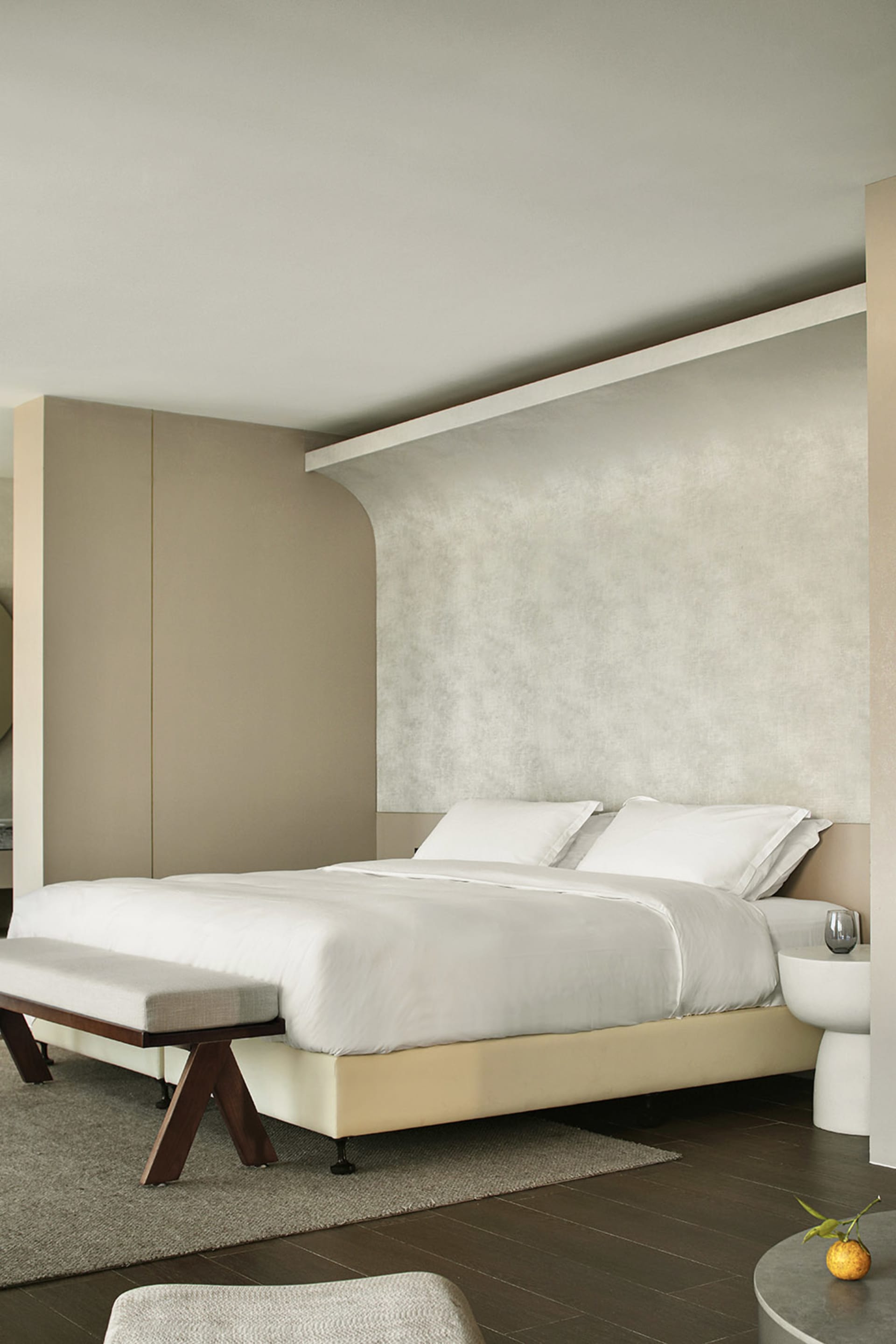 A modern minimalist bedroom featuring a white bed with white bedding.