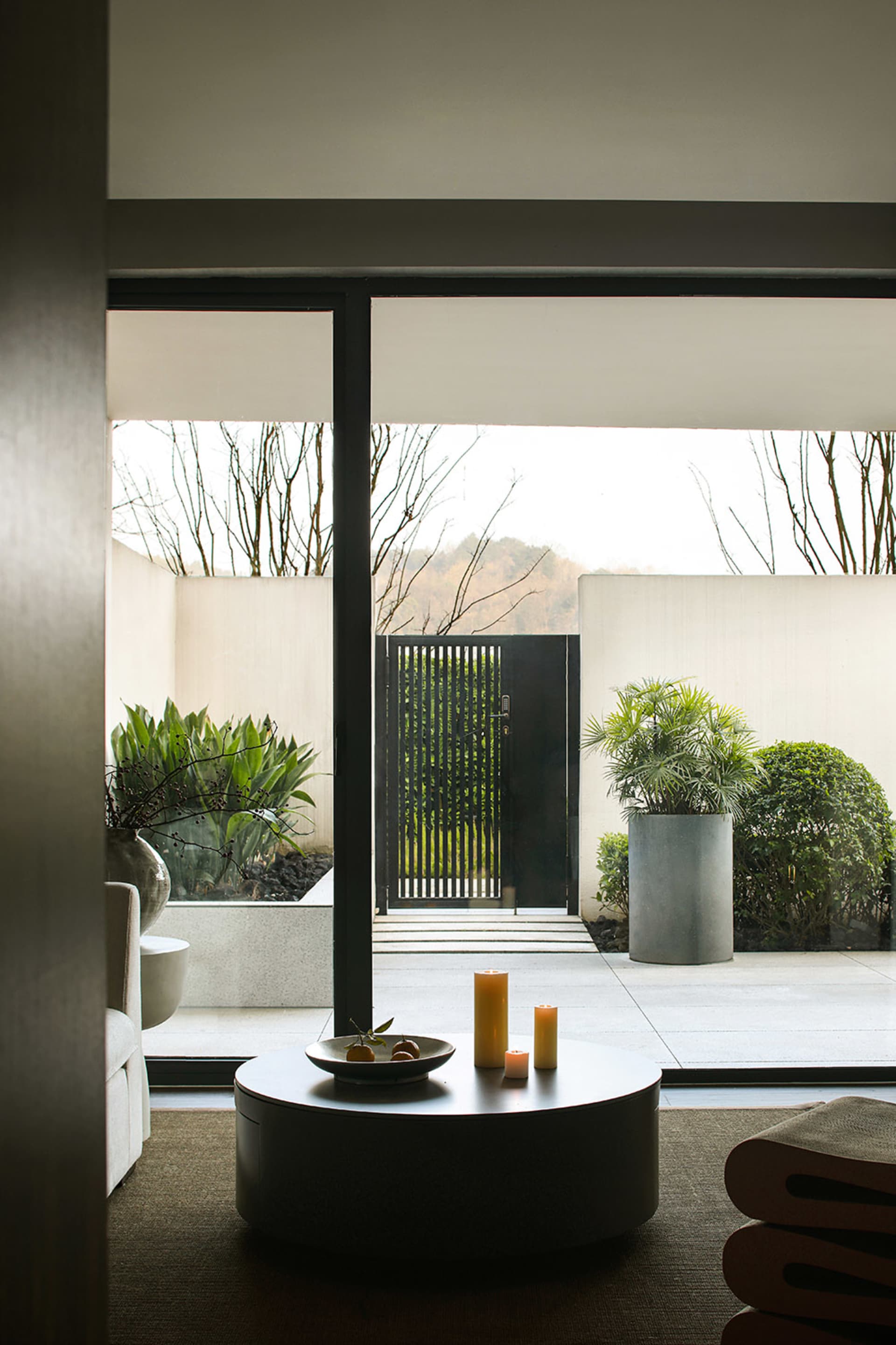 A modern minimalist living room with concrete, glass, and metal elements.