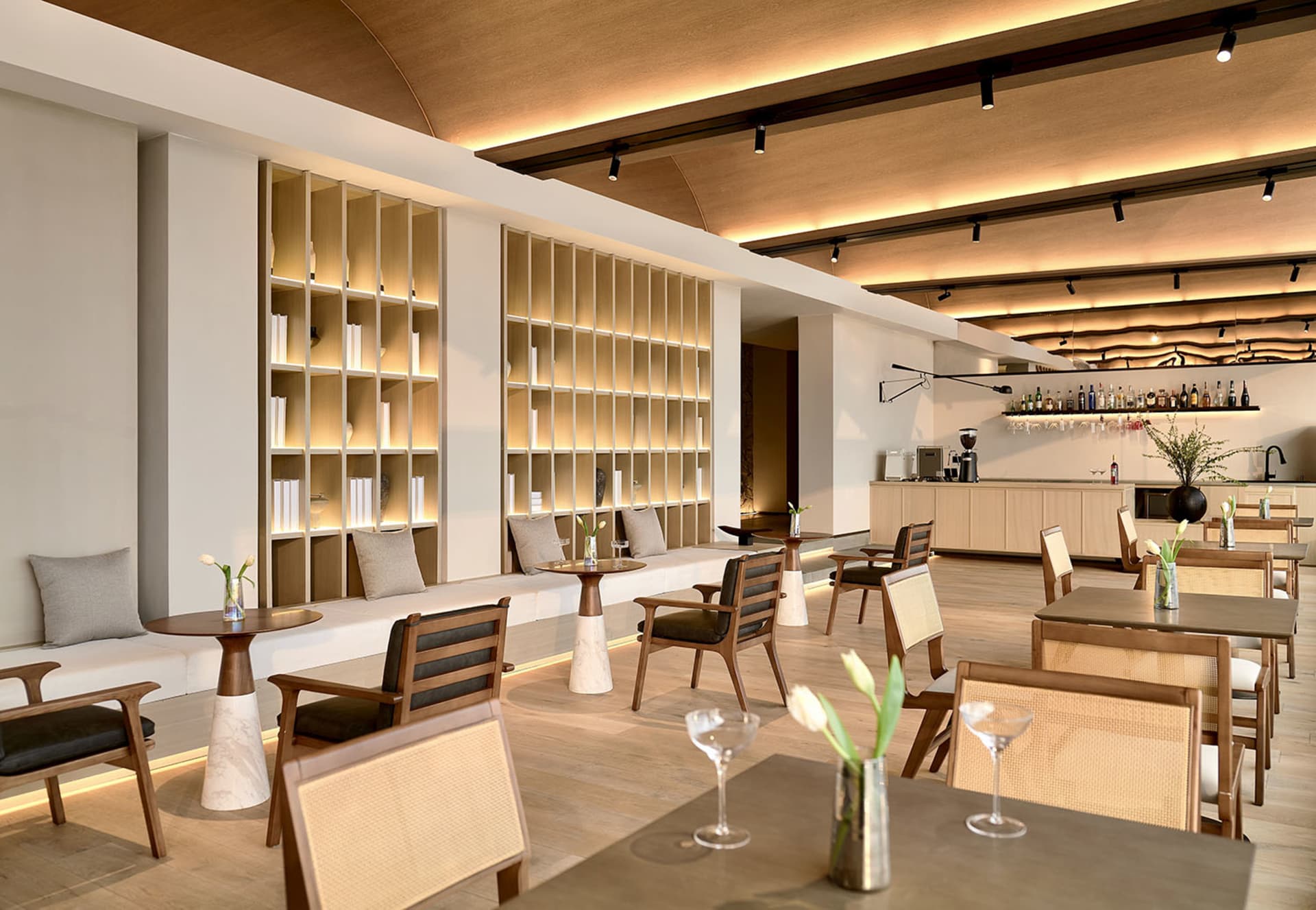 An elegant modern restaurant and bar interior featuring wooden furniture, marble accents, and glass displays.