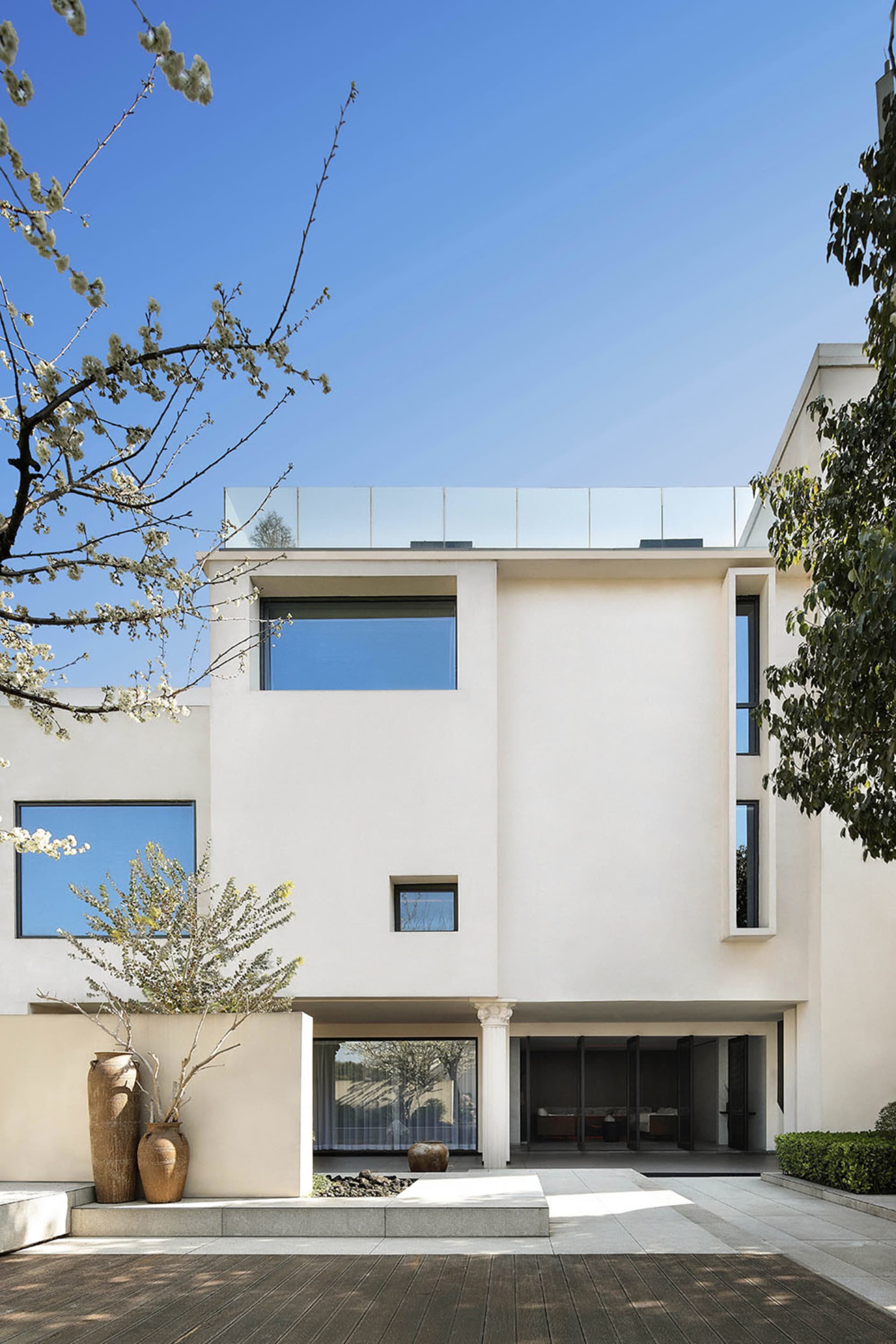 A modern residential house with white rendered concrete exterior and large glass windows.