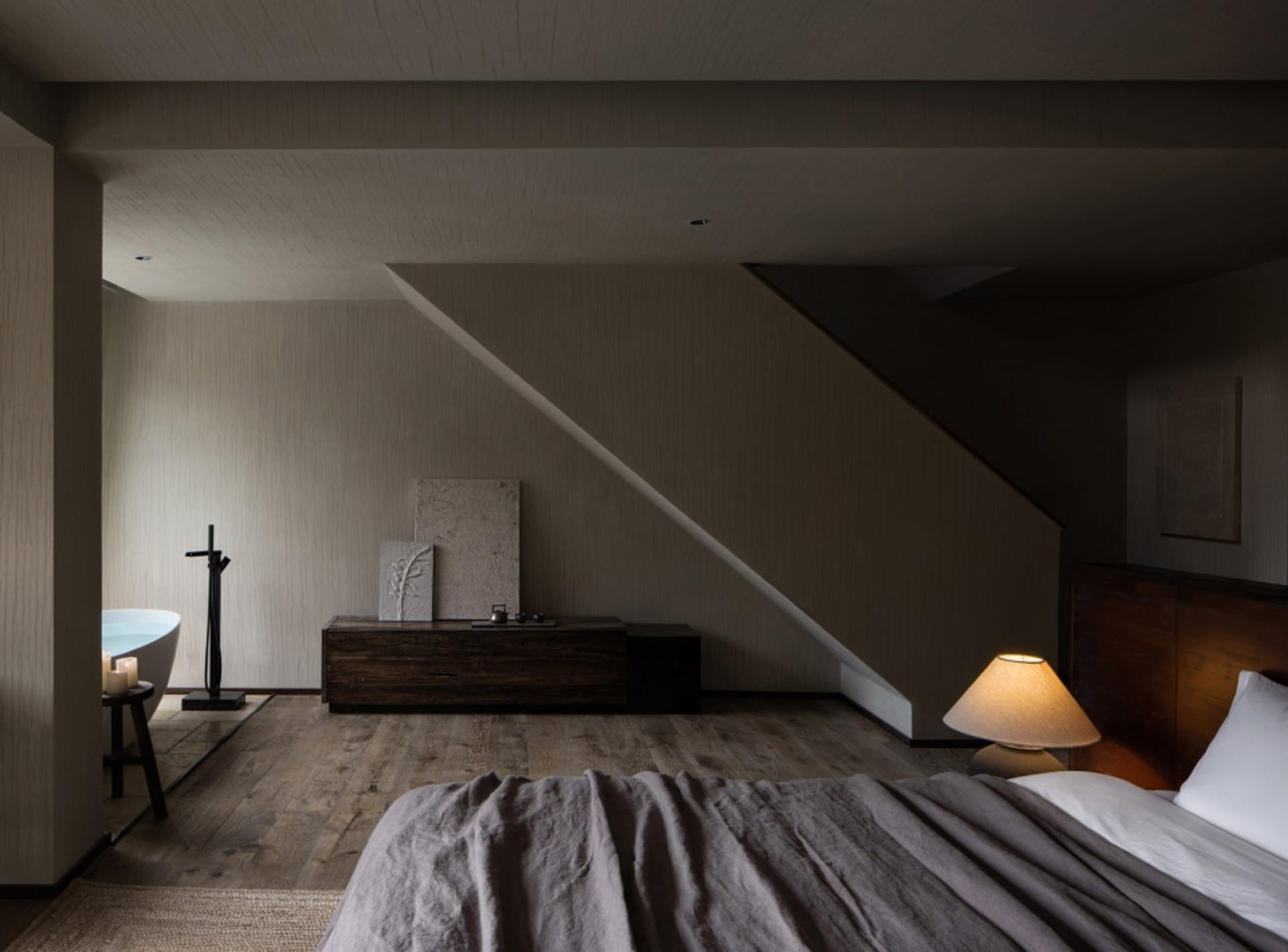 A modern bedroom features wooden furniture and a cozy ambiance with a lit lamp.