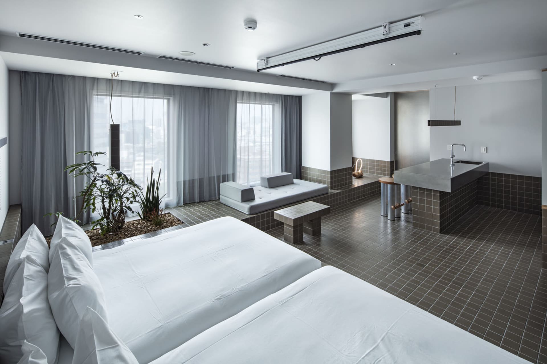 Modern hotel room with concrete tiles, plants, and minimalist design