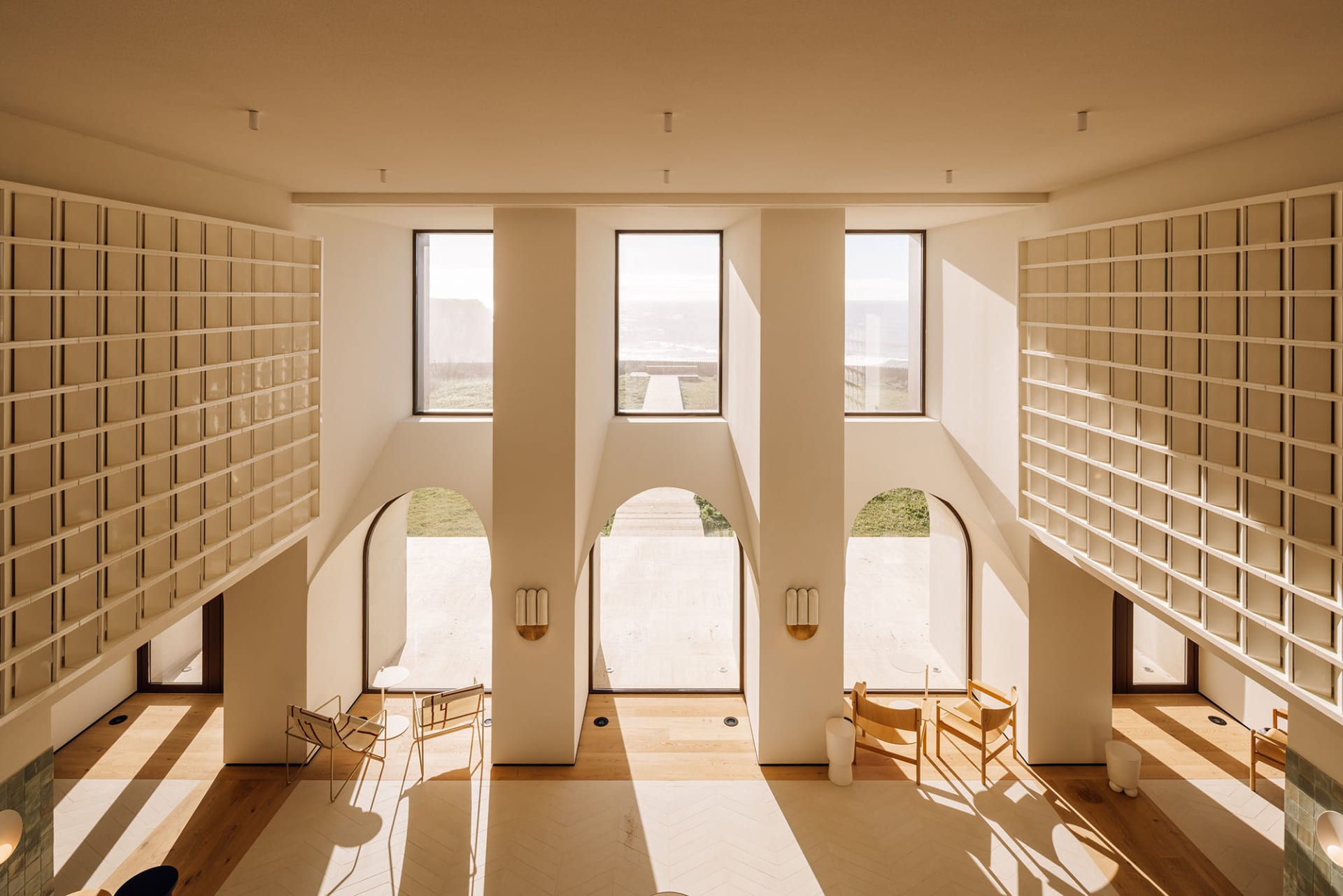 Modern interior design featuring exposed concrete walls, large windows, and warm lighting.