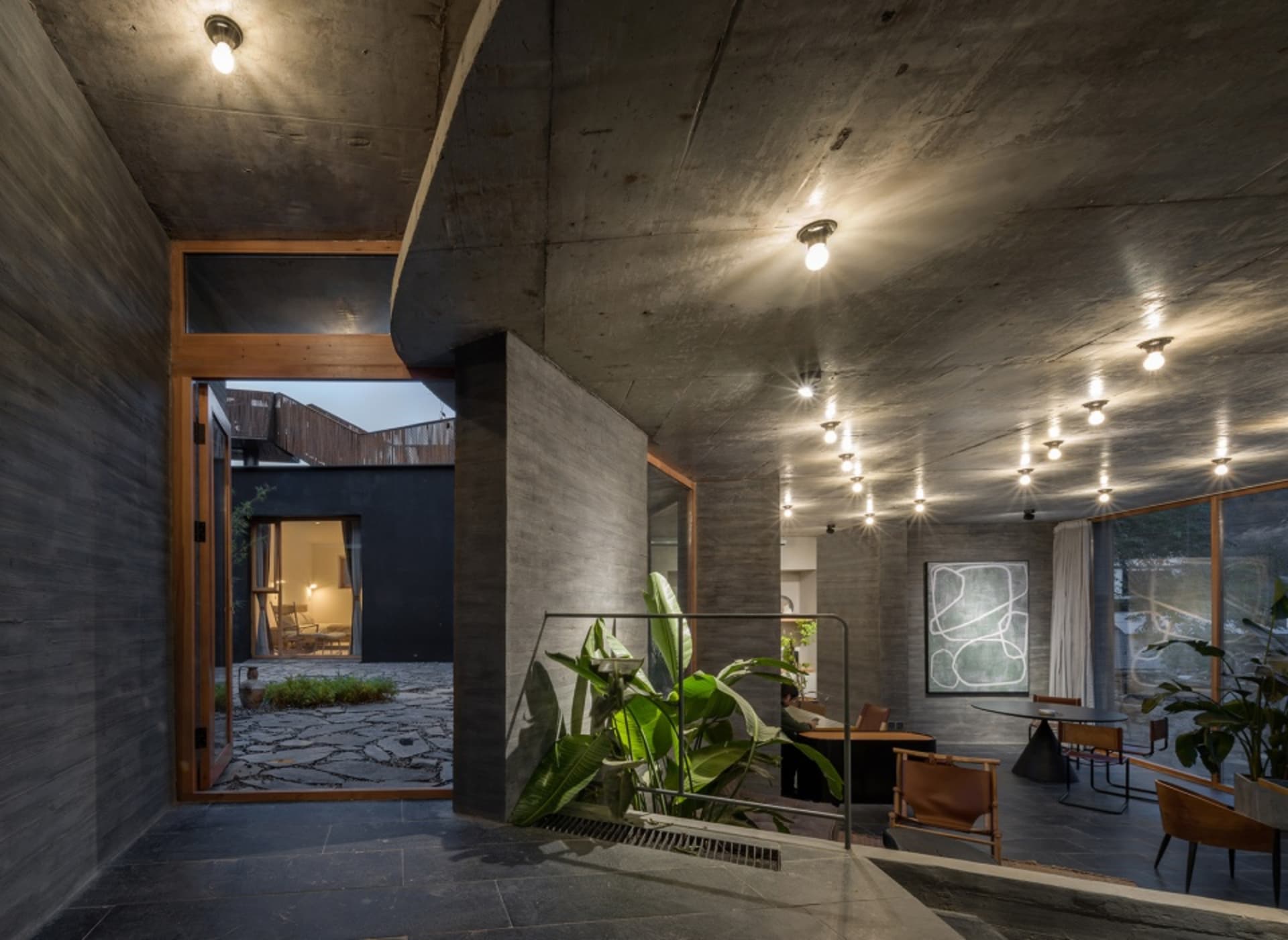 Modern, industrial-style living space featuring concrete walls, exposed beams, and minimalist furniture.