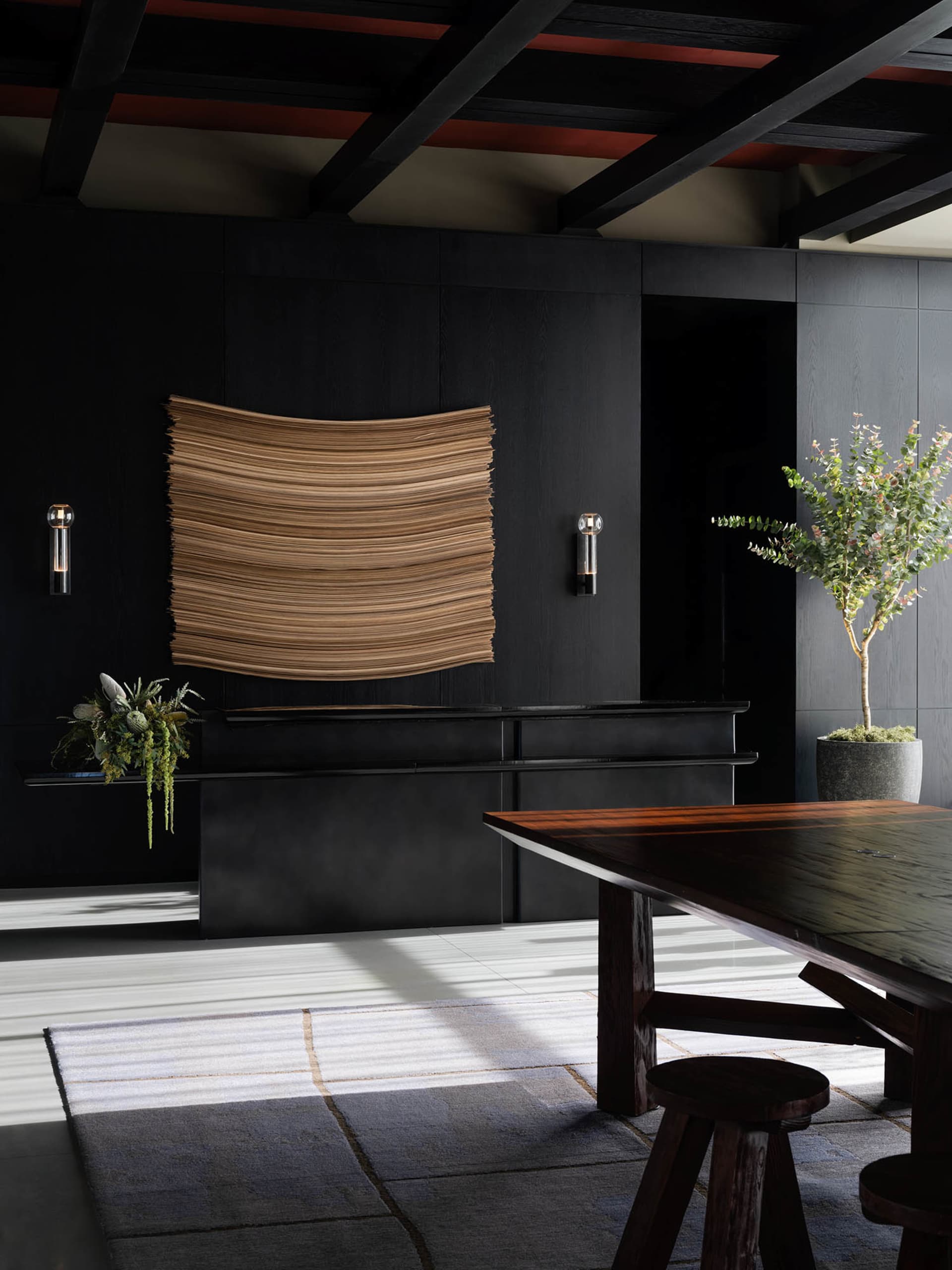 A modern living room featuring wooden furniture, a large window, and a vase with flowers.