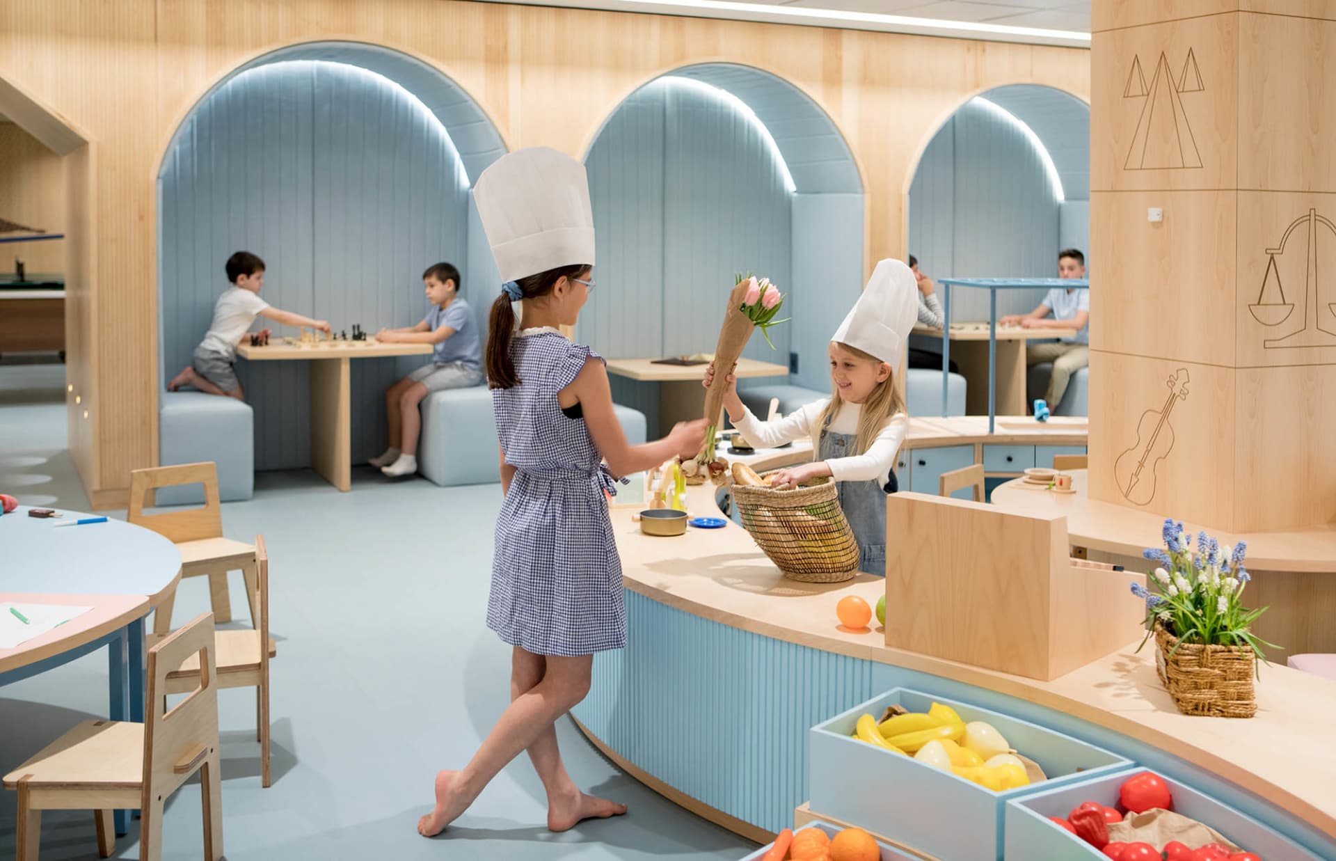 Children playing in a modern, brightly lit playroom with wooden furniture and natural materials.