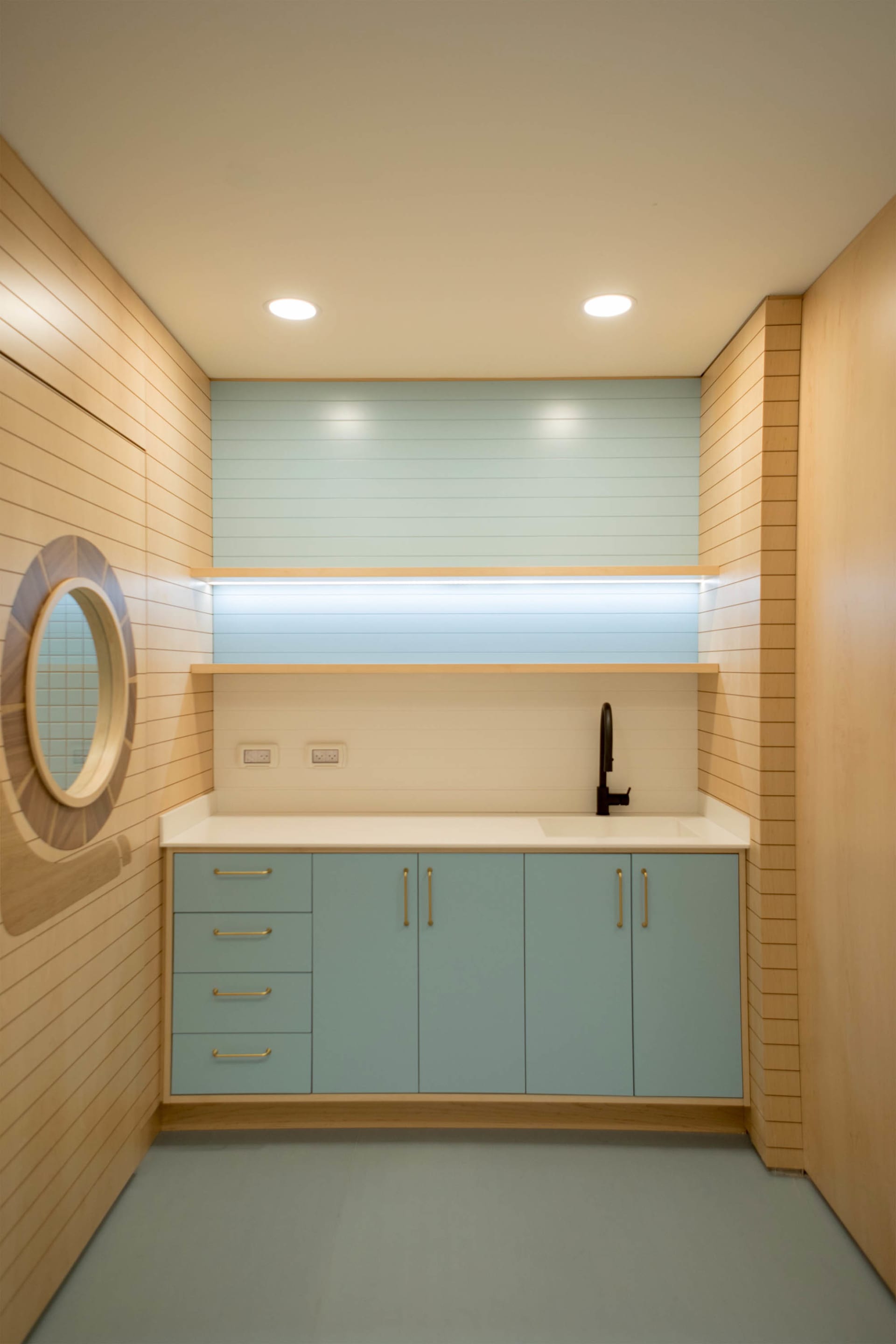 A modern residential laundry room designed with wooden and plywood walls, featuring a sink and storage cabinets.