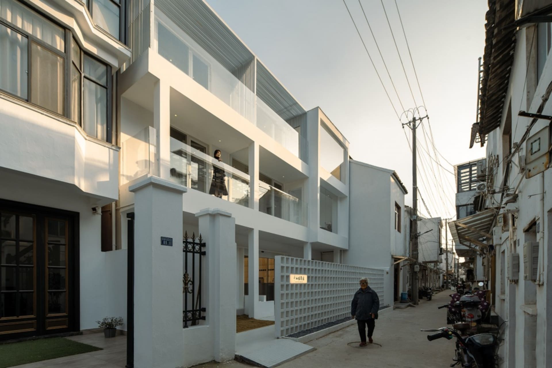 Modern residential building with white walls, glass windows, and metal railings and doors.