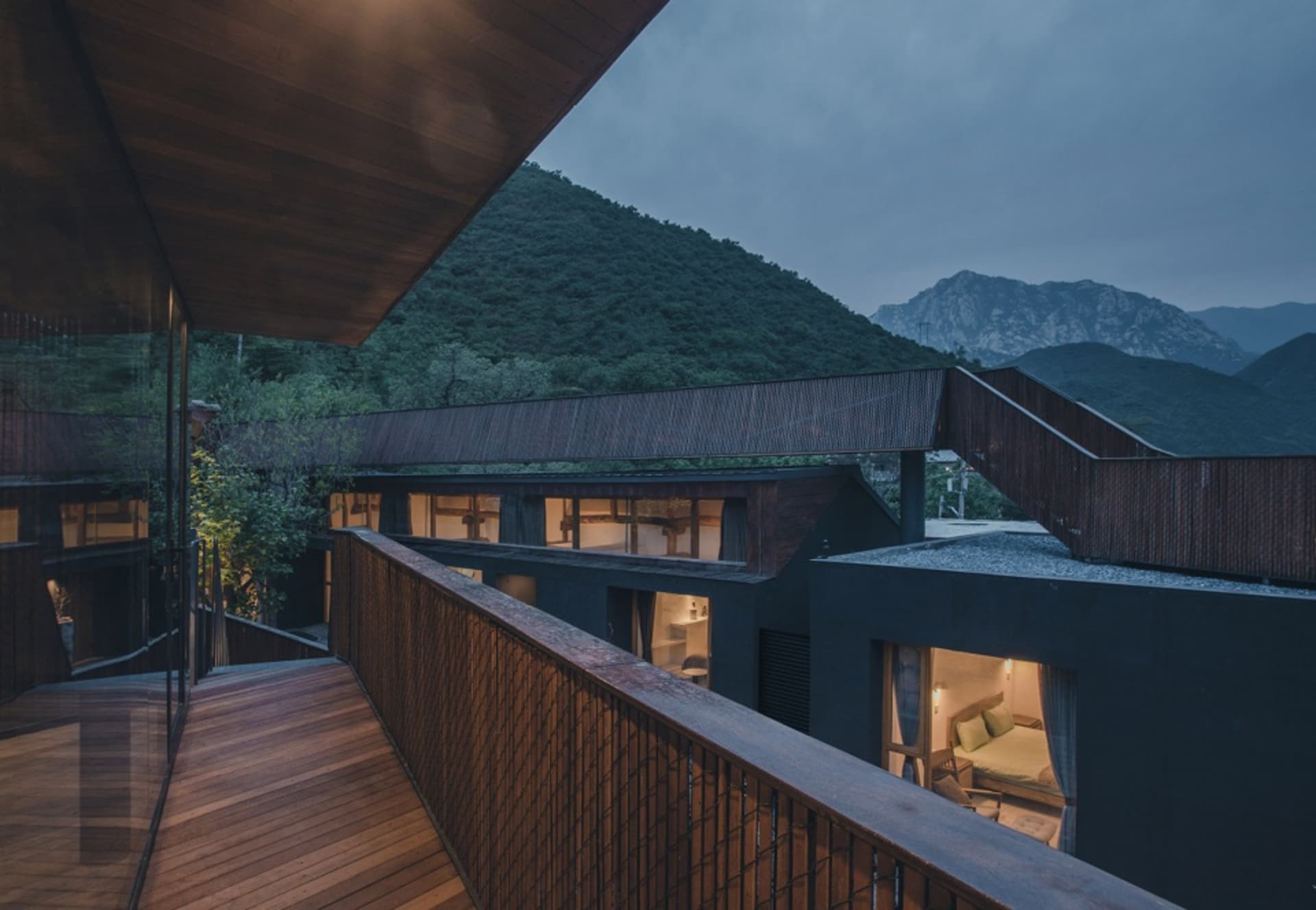 A wooden terrace overlooking a residential area with mountains in the background.