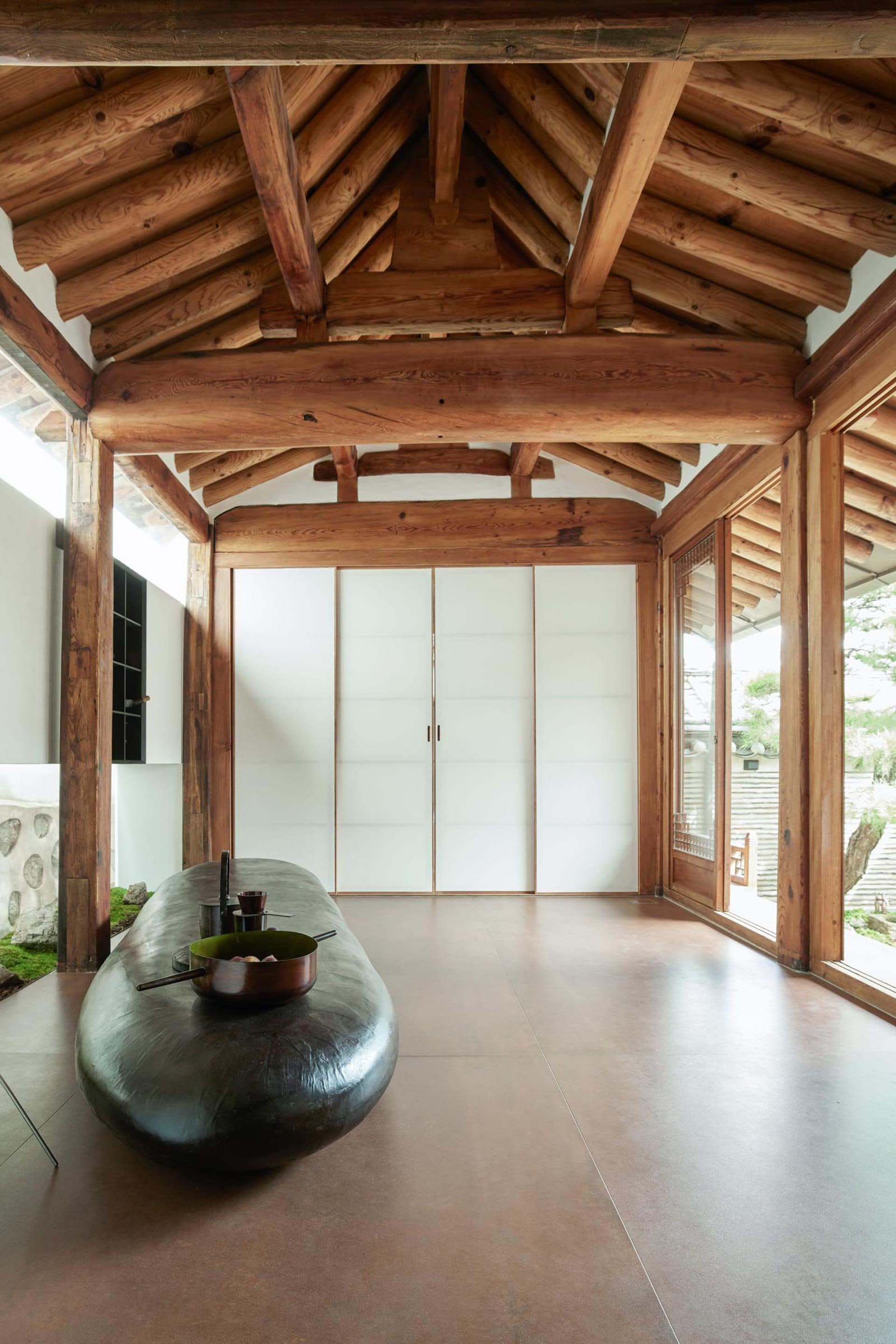 Traditional room with wooden beams, white sliding doors, and a long wooden bench.
