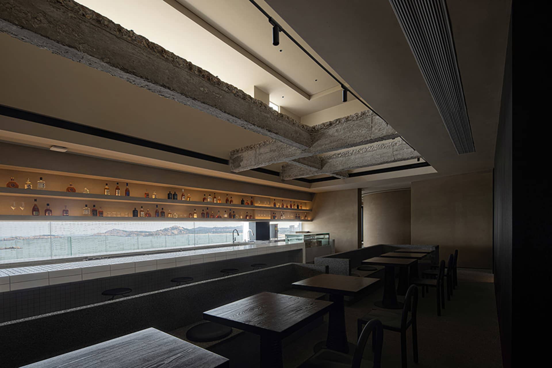 A modern bar interior with concrete counter and seating areas
