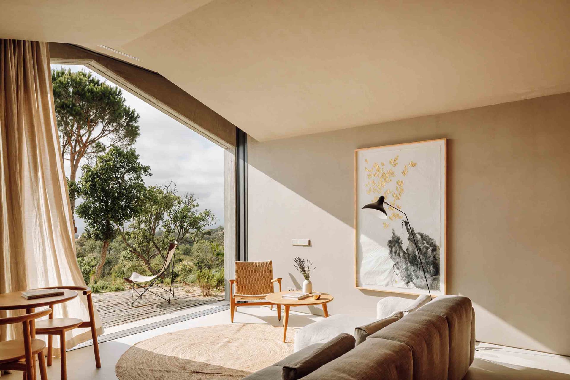 Modern living room with minimalist design featuring neutral tones, natural light, and a blend of organic and geometric shapes