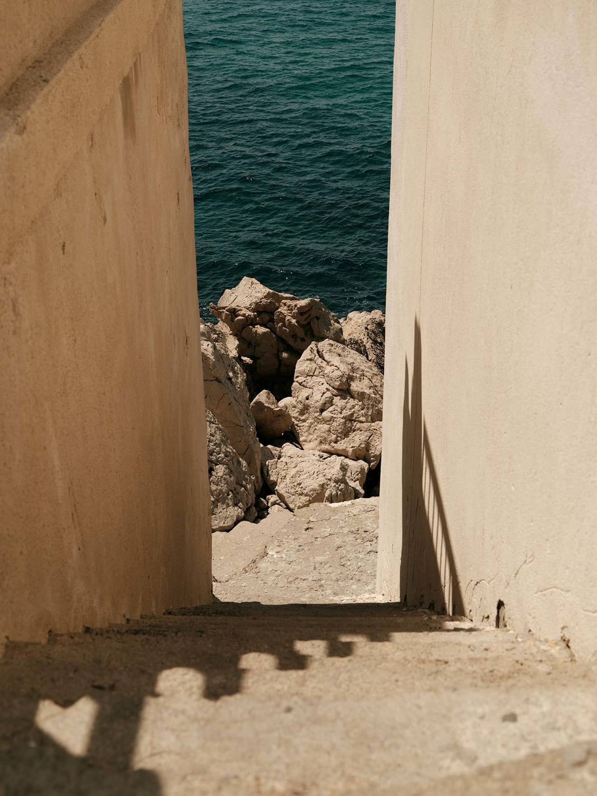 A concrete pathway leading to water, framed by tall walls.