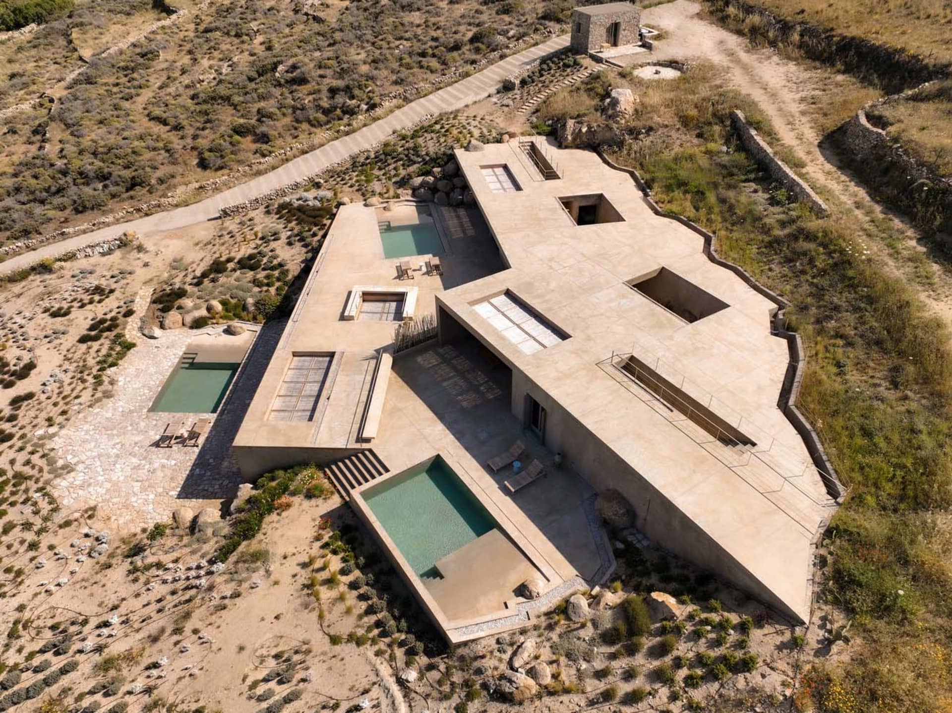A modern house with a concrete exterior featuring pools and an exposed floor plan.