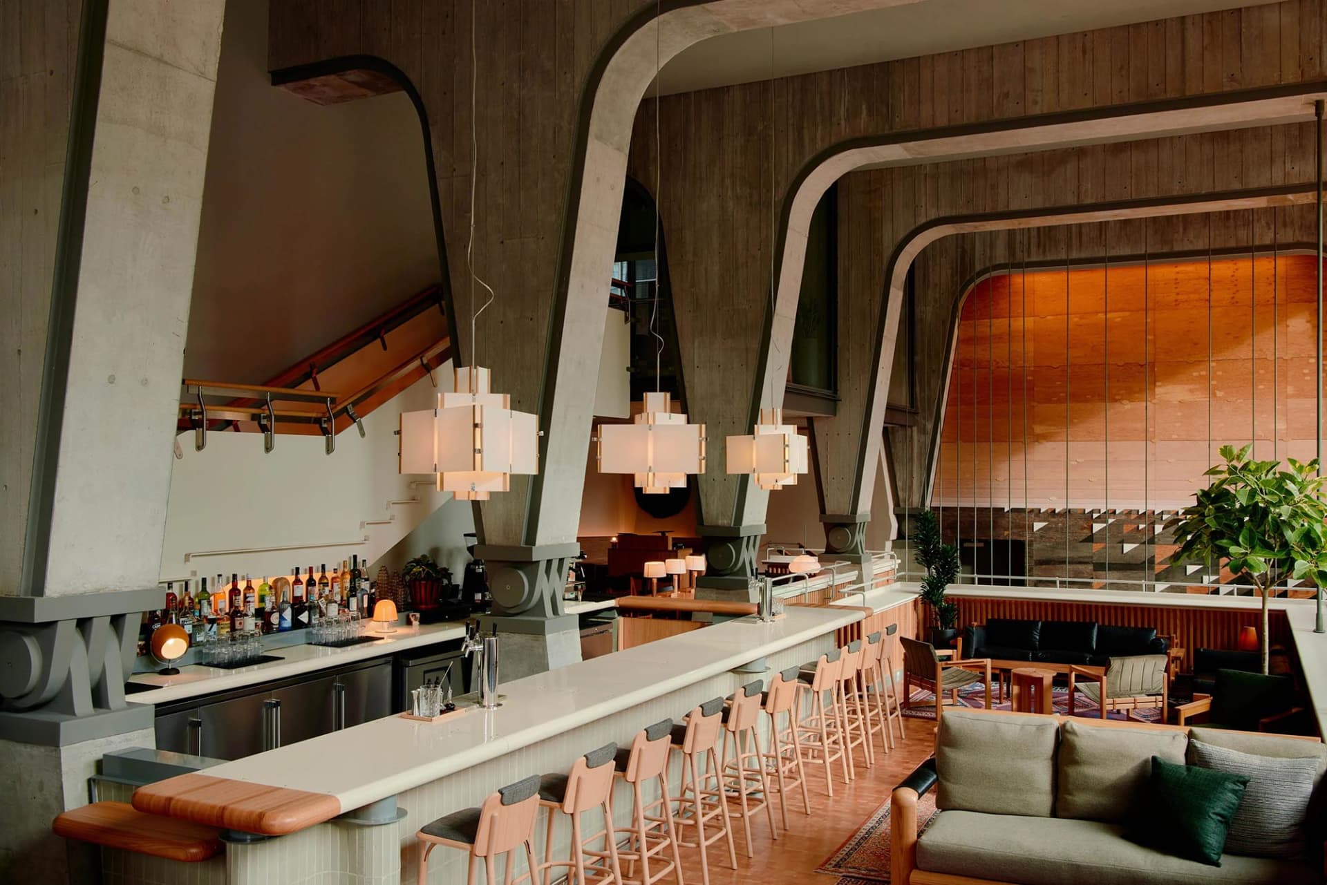 Modern bar lounge area with concrete and wooden elements, featuring a bar counter and seating.