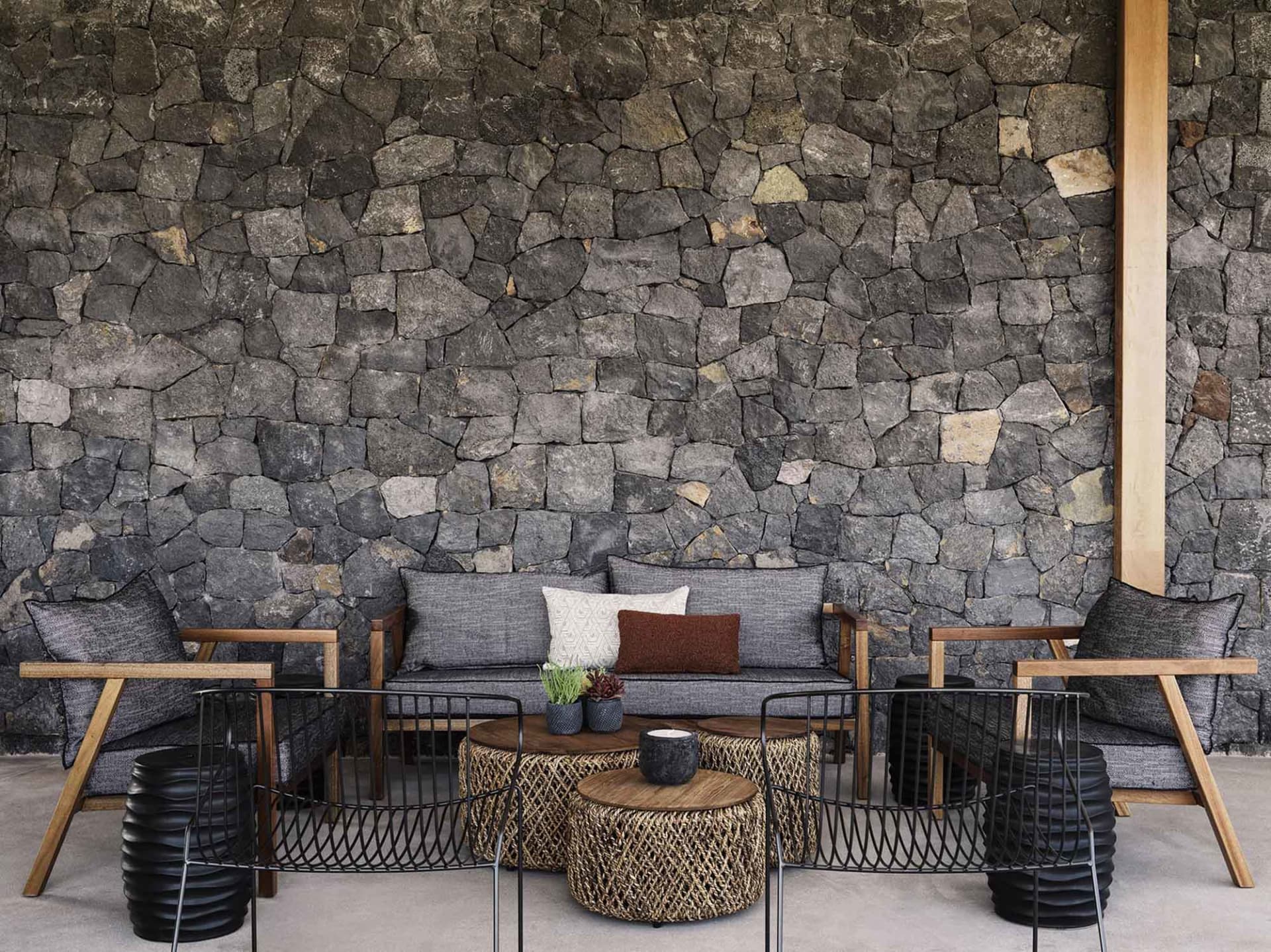 A living room with a natural stone wall and upholstered furniture.