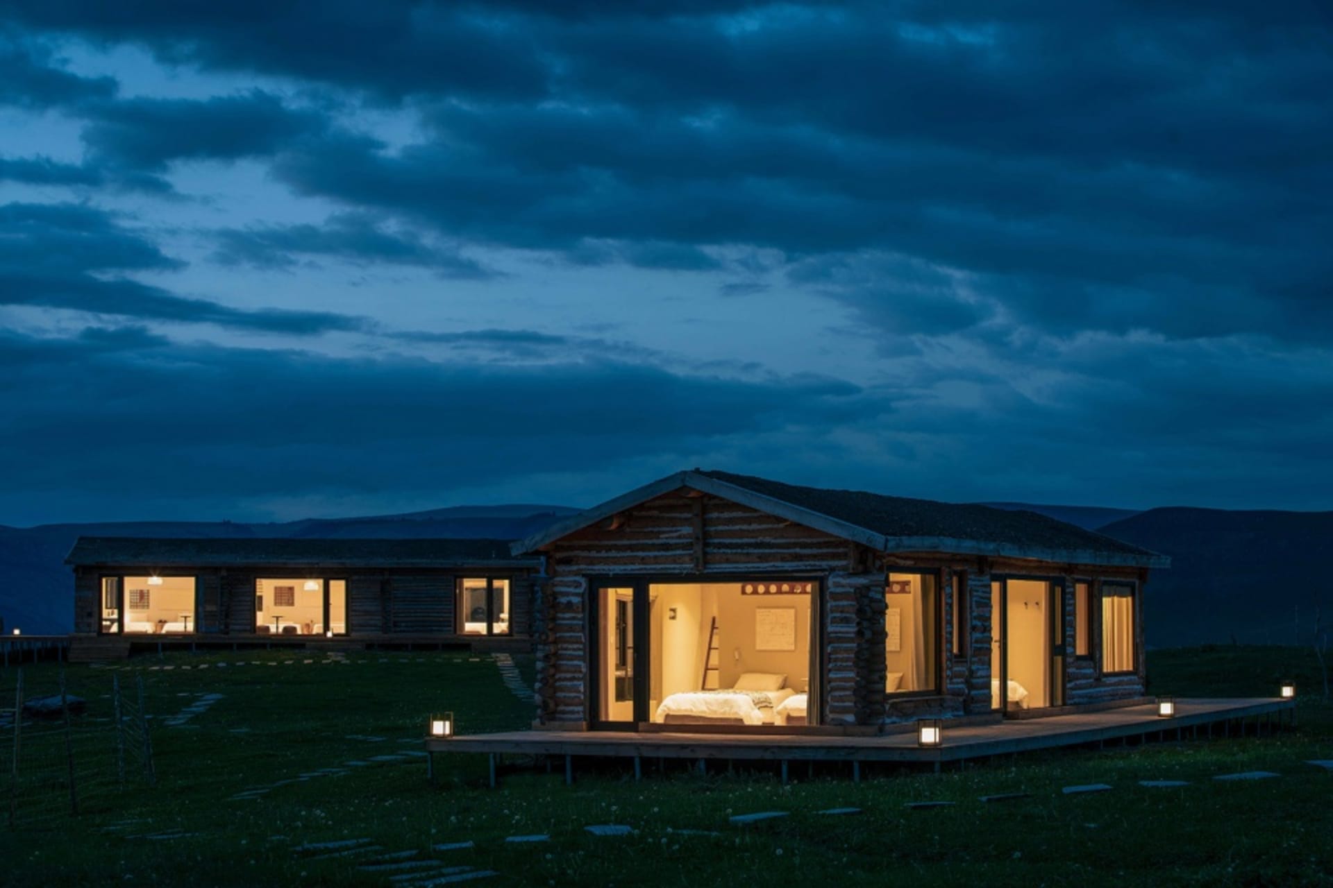 A rustic home with wooden exterior and illuminated windows at night.