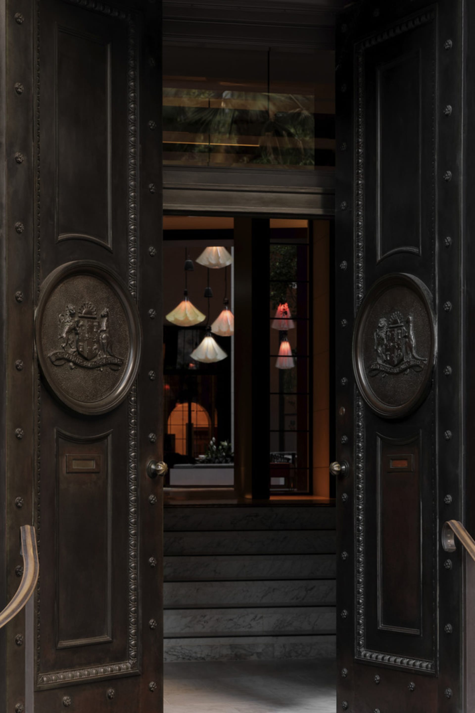 A luxurious hotel lobby with black metal doors adorned with leather and marble