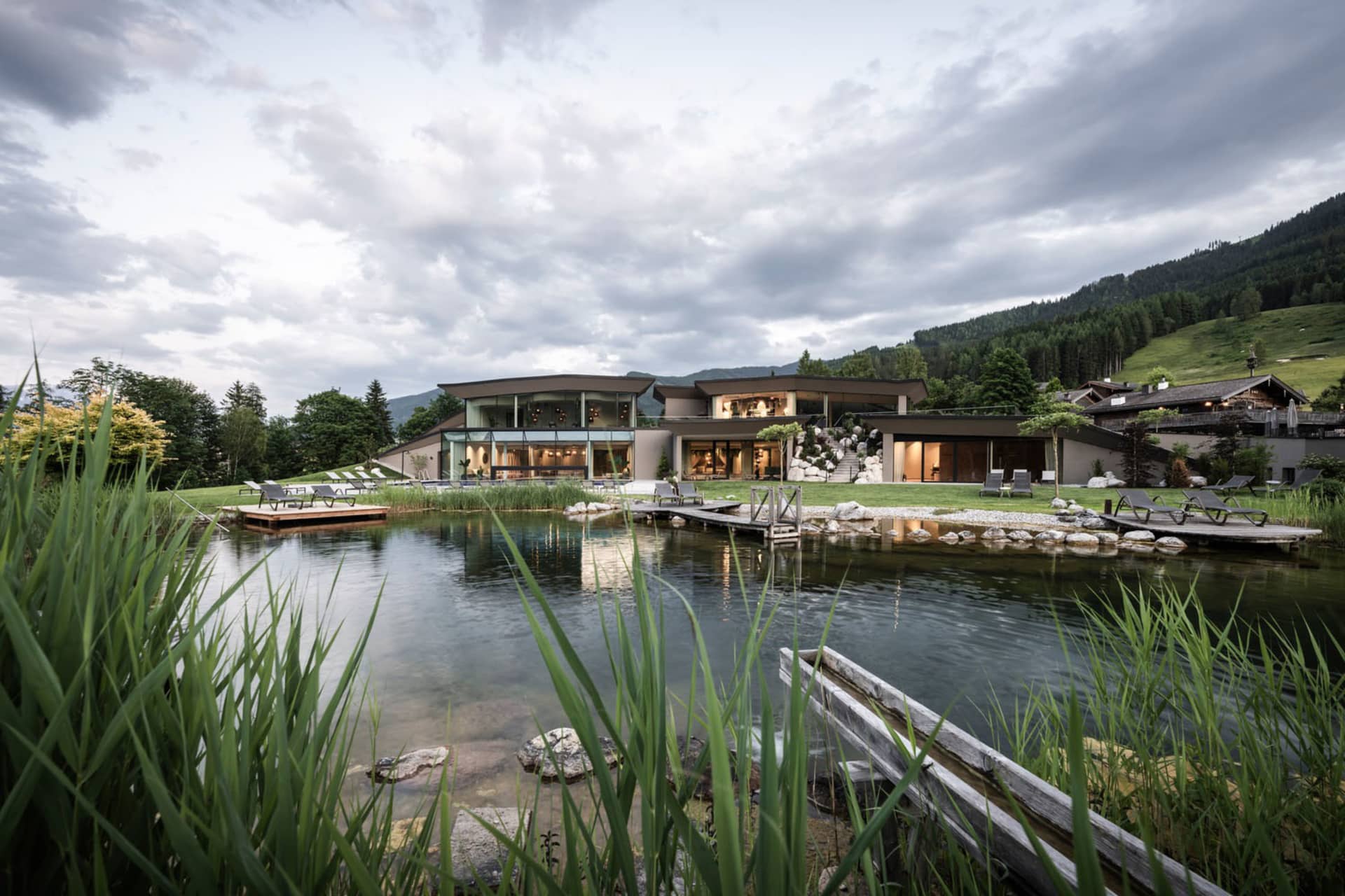 A modern architectural residence featuring glass walls and stone pathways by a serene water feature.