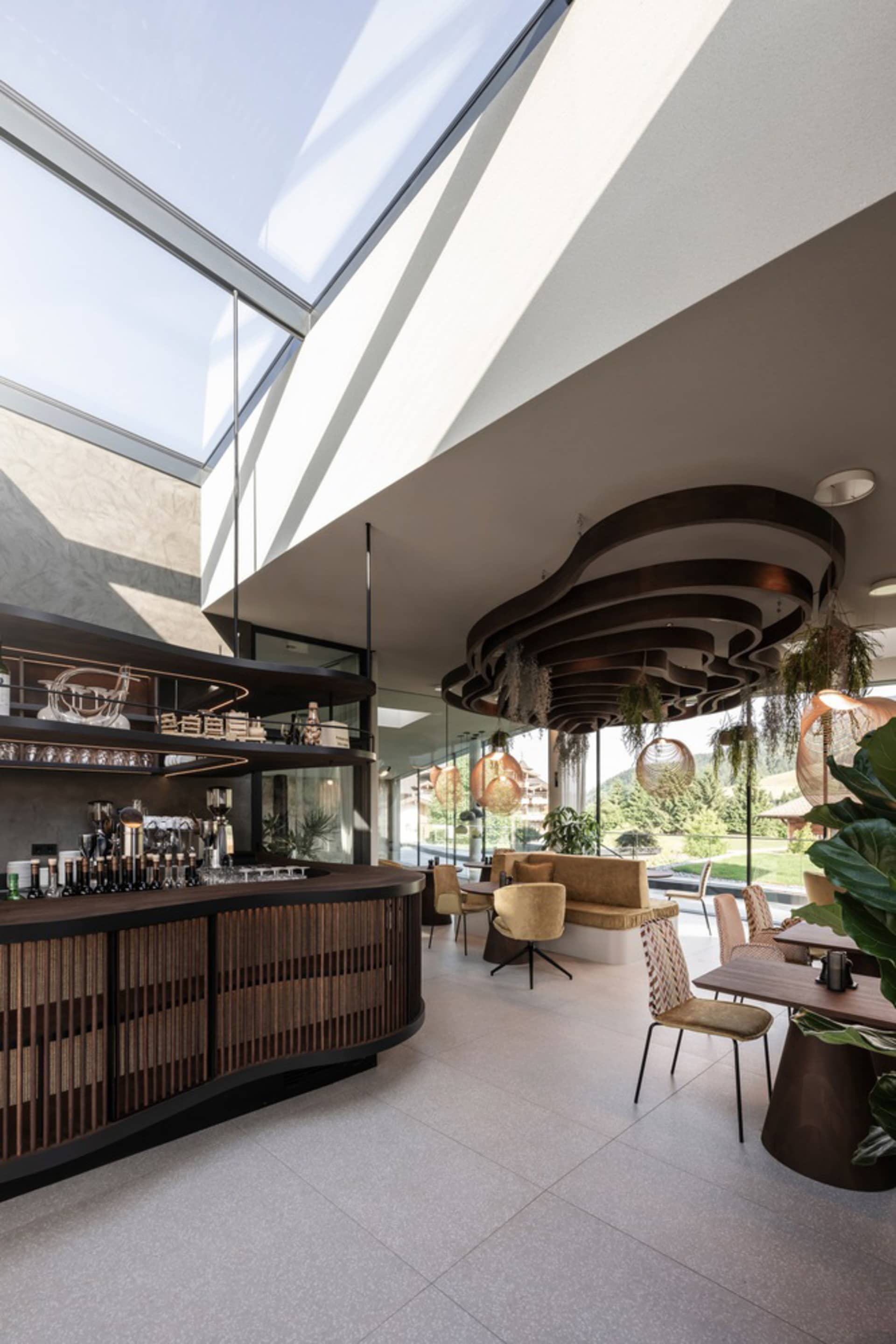 A modern cafe bar with a glass ceiling, wooden counter, and metal chairs.