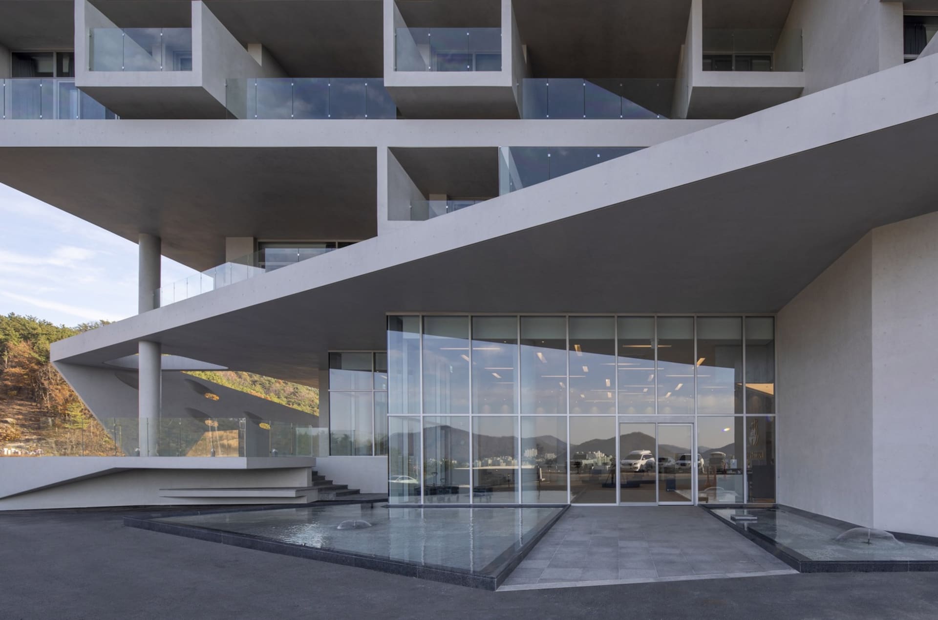 A modern concrete building with glass windows and a spacious entrance.