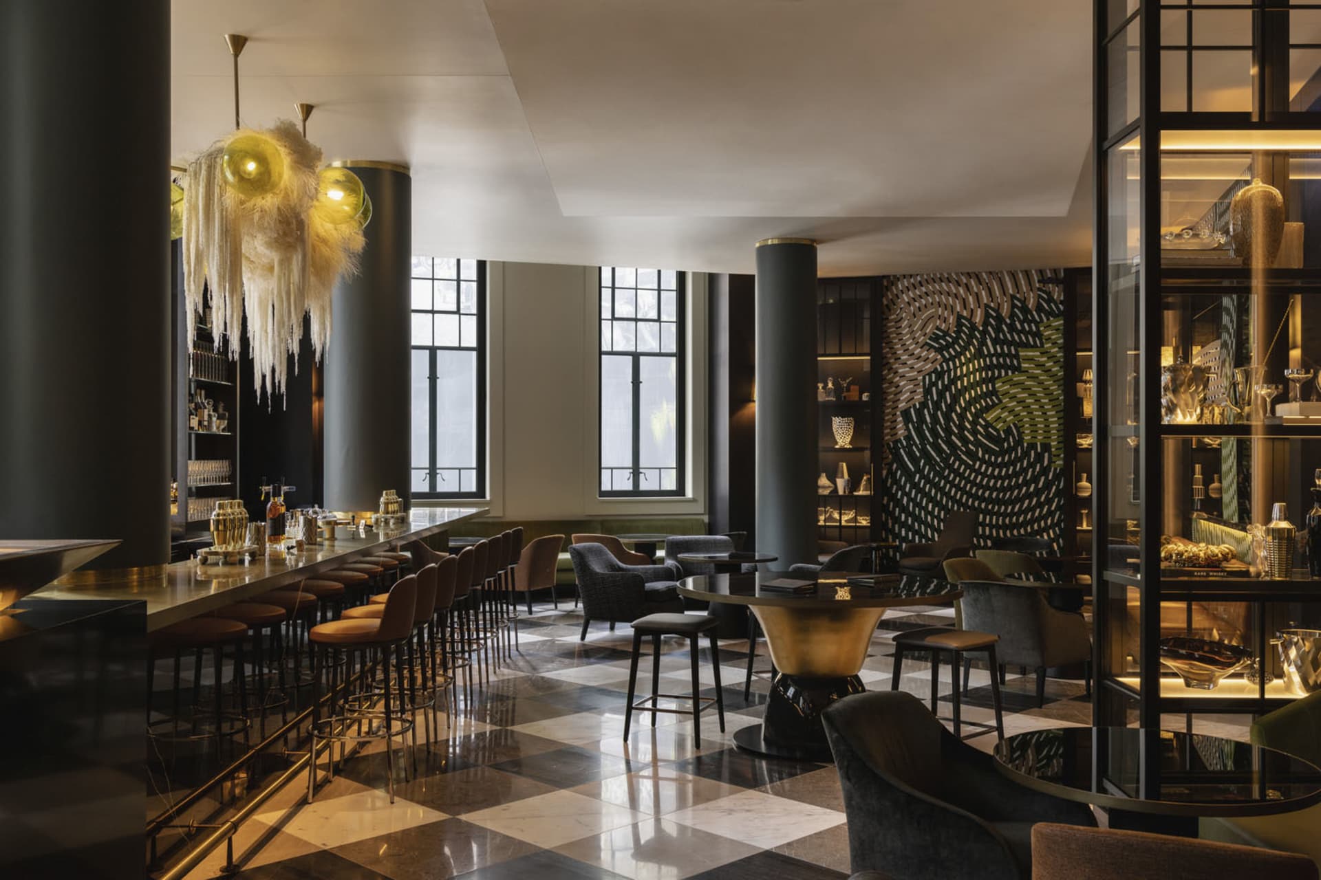 A modern hotel bar featuring metallic, glass, and marble elements.