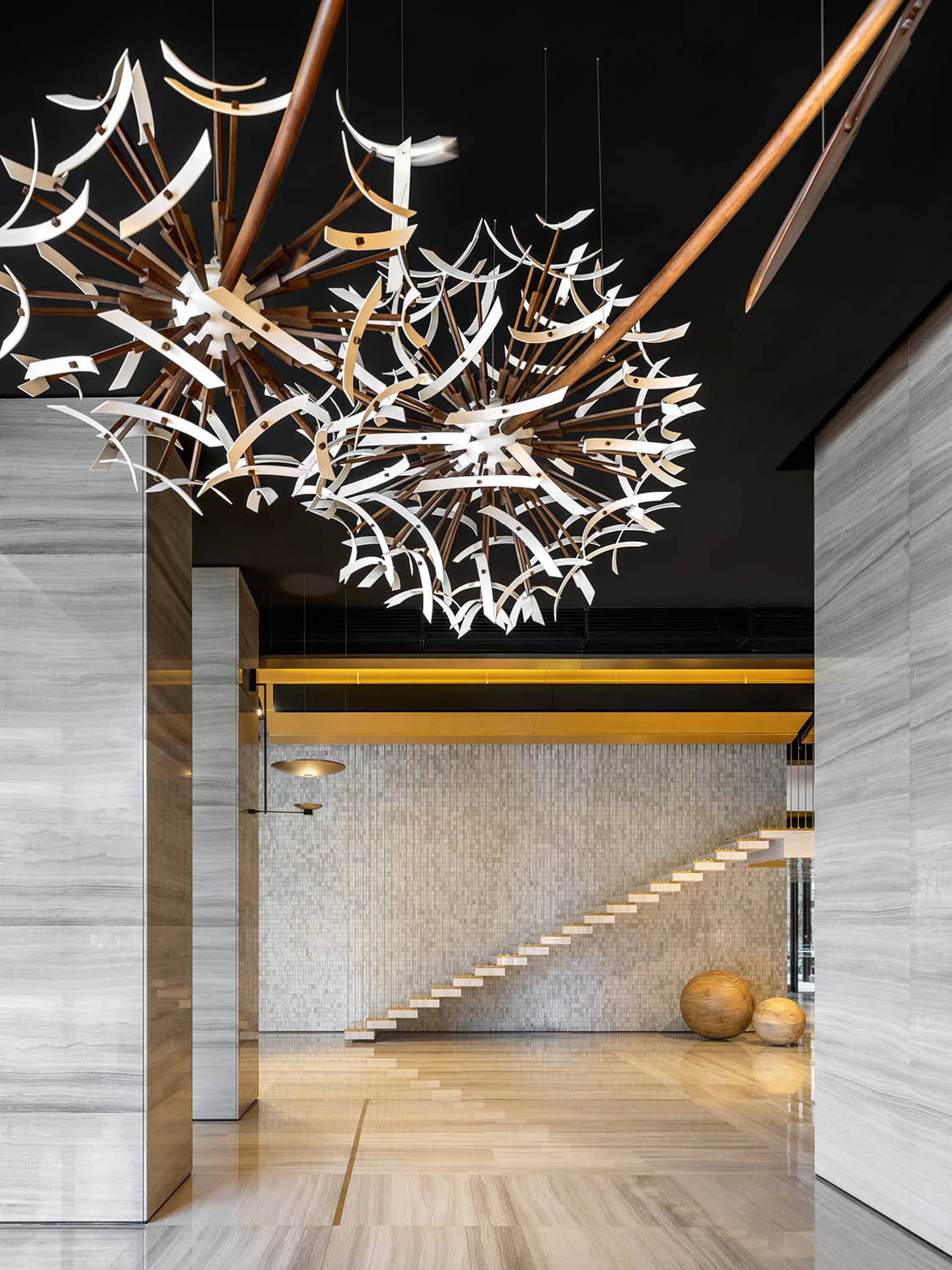 Modern lobby interior featuring marble flooring and wooden light fixtures.