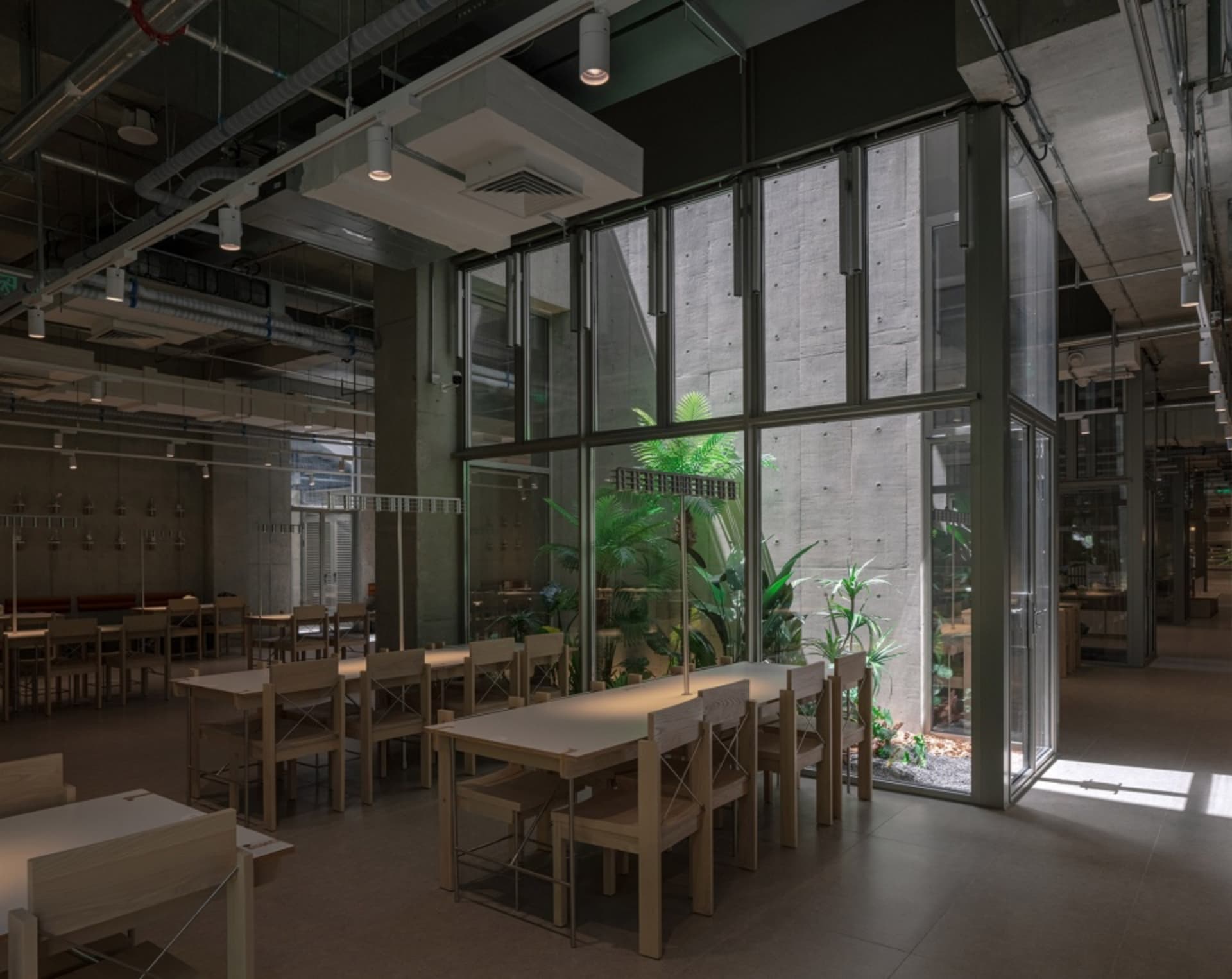 A modern office cafeteria with concrete, glass, and wooden elements.