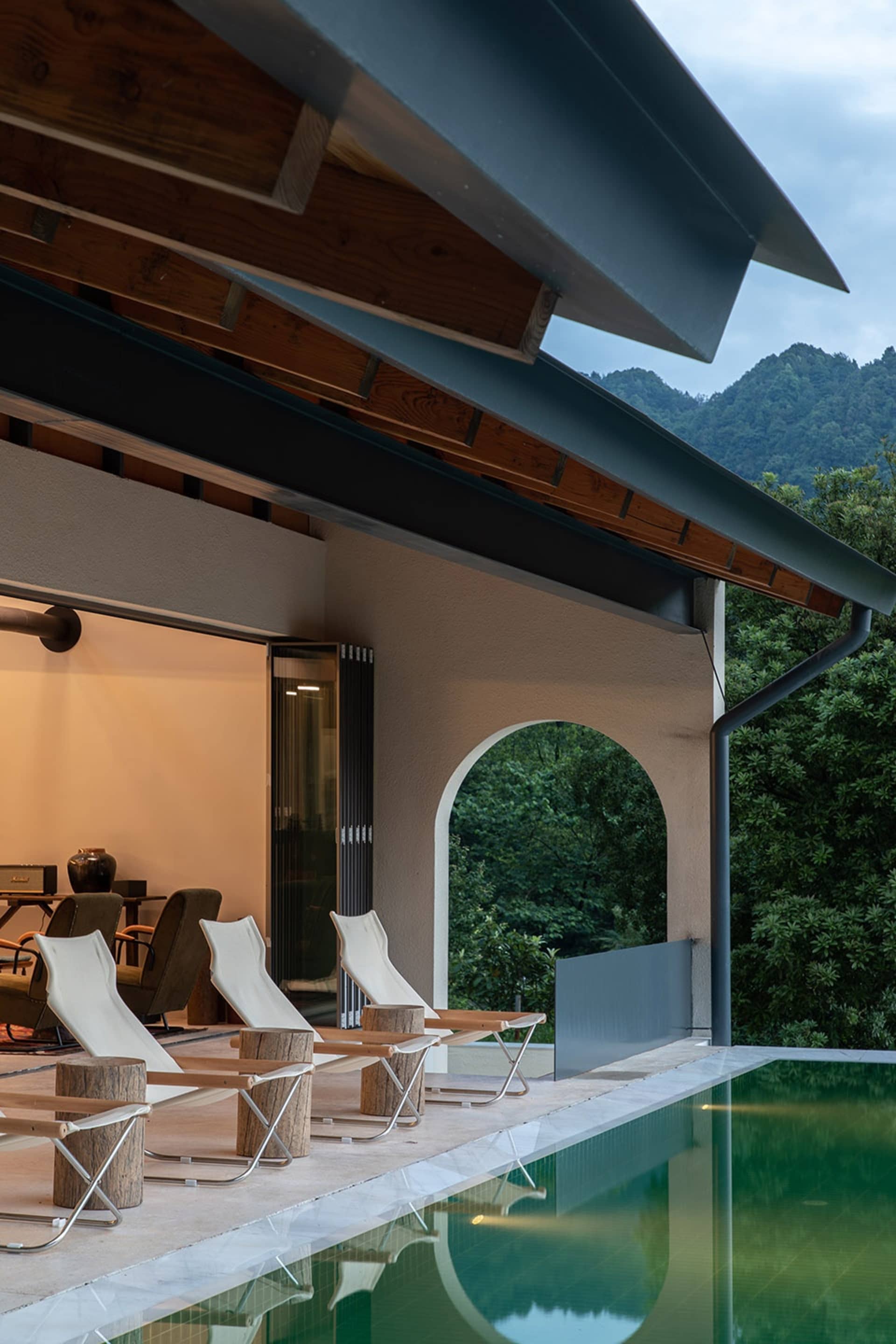 Modern residential home featuring a concrete poolside area with lounge chairs and a view of the mountains in the background.
