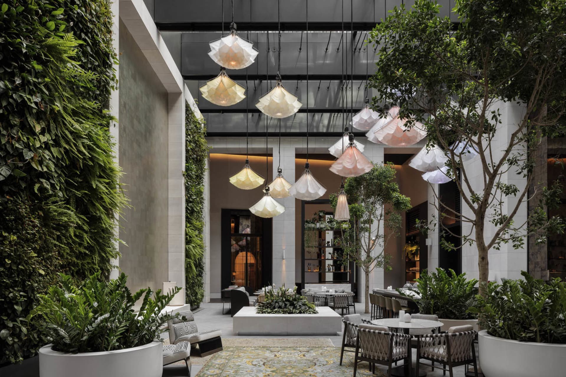Modern restaurant interior with glass lampshades, concrete surfaces, and potted plants.