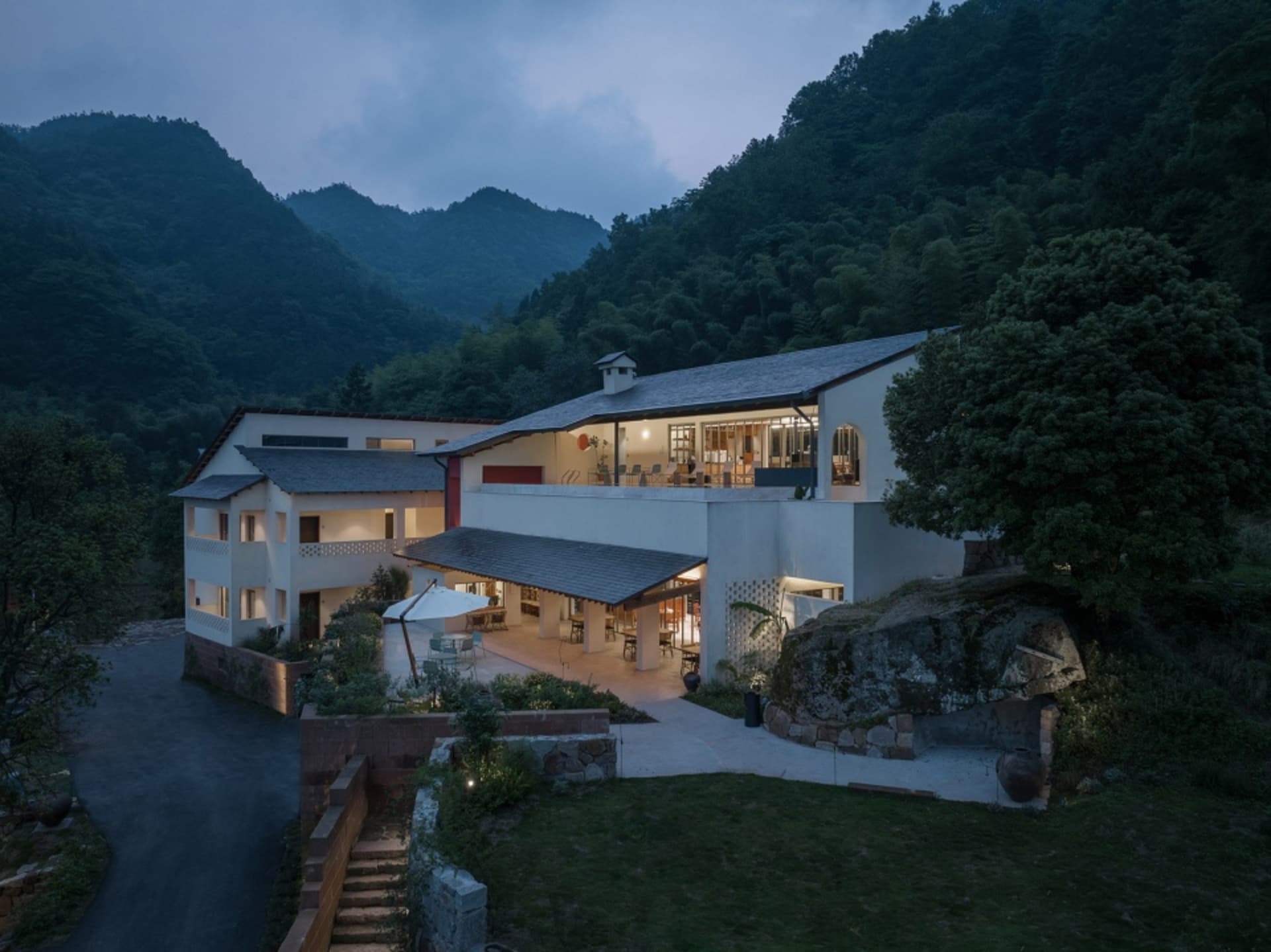一座現代山居,採用混凝土與玻璃材質,置於寧靜的戶外環境中。