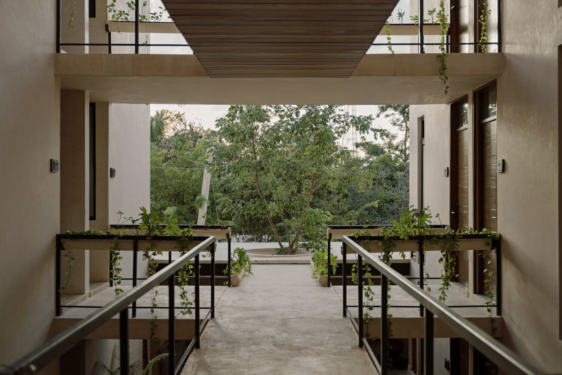 A spacious, modern residential patio with concrete flooring and lush greenery.