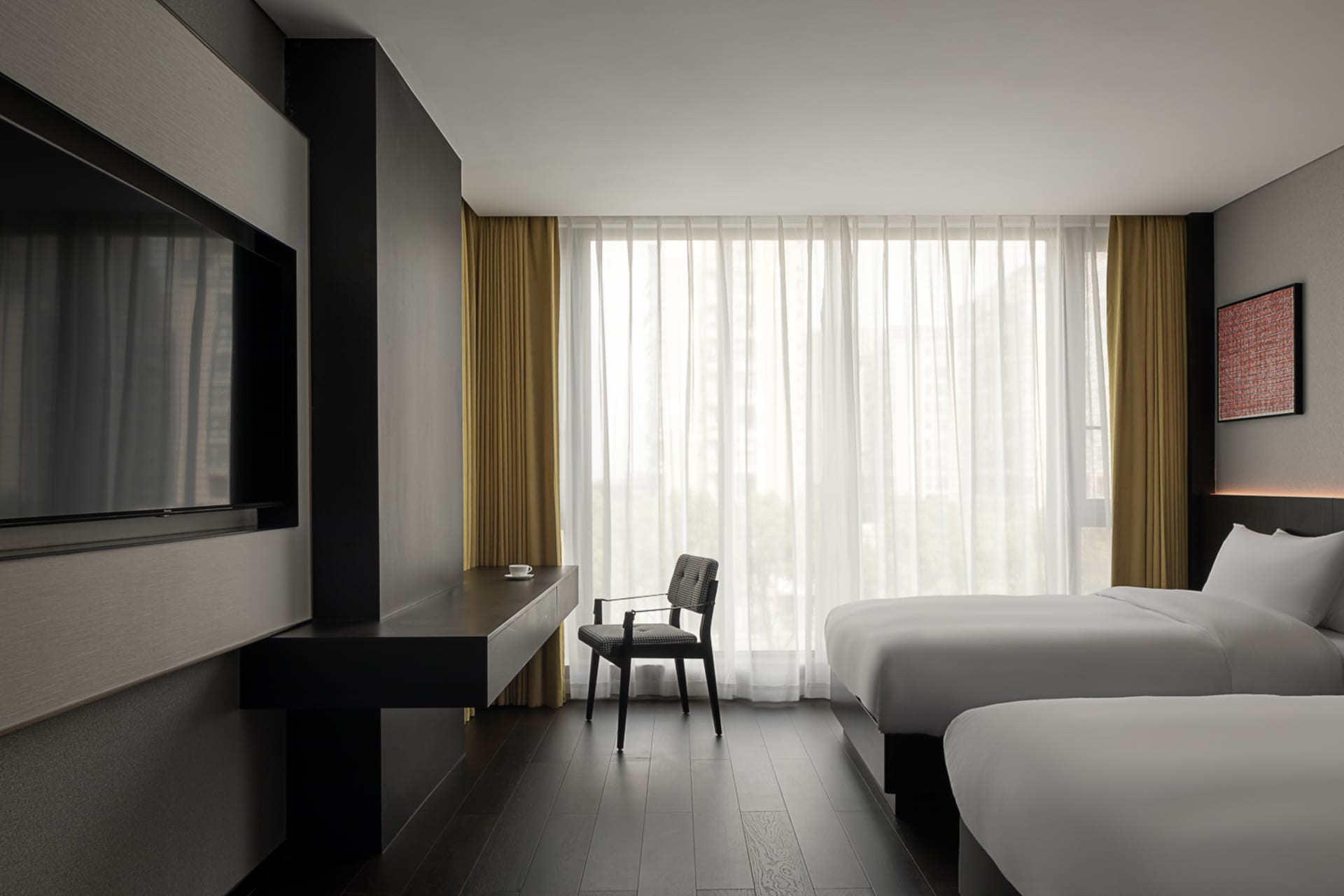 Minimalist hotel bedroom with two white beds, white linen, yellow curtains, and dark wood flooring.