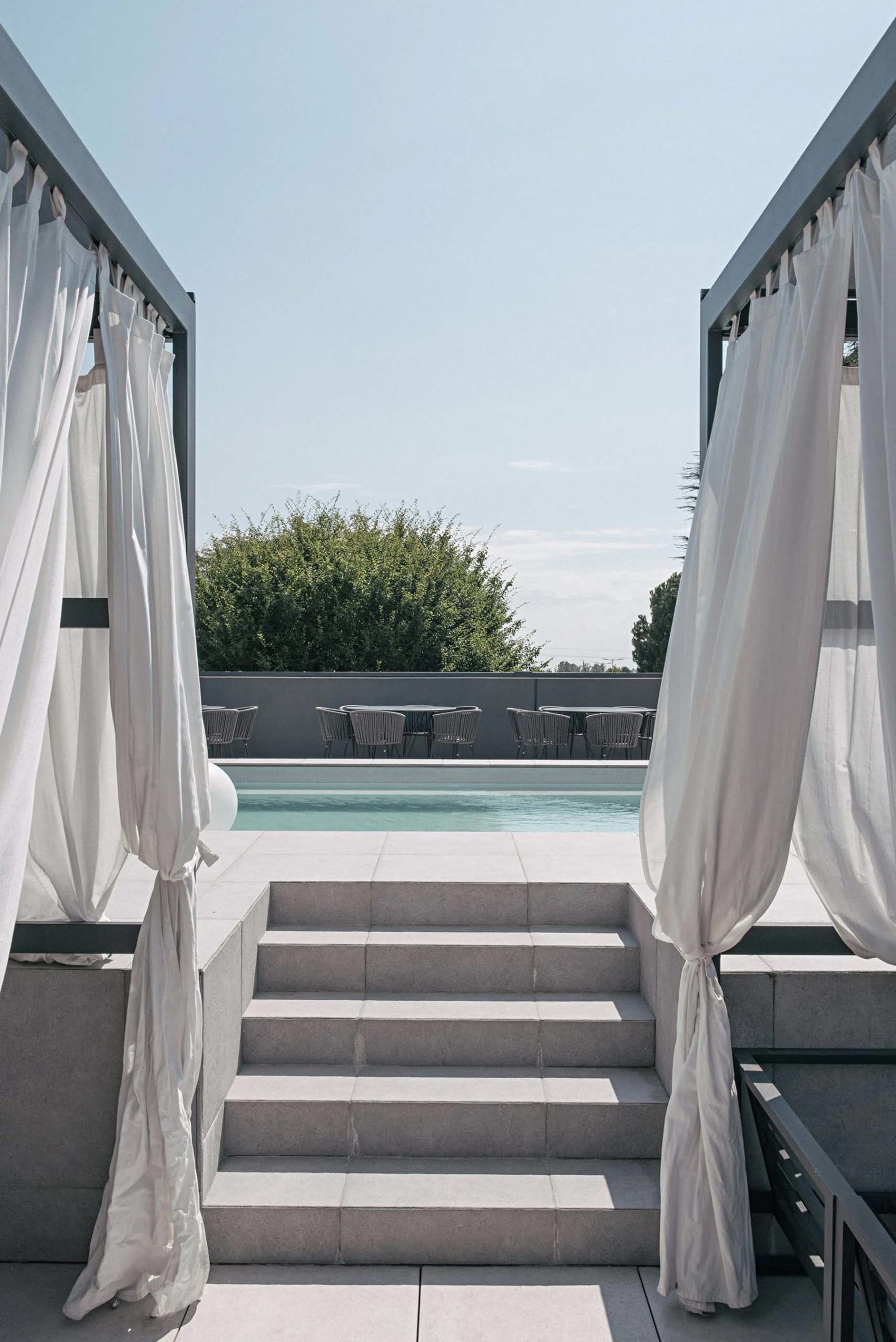 Concrete steps leading to a minimalist residential landscape with seating area and pool.