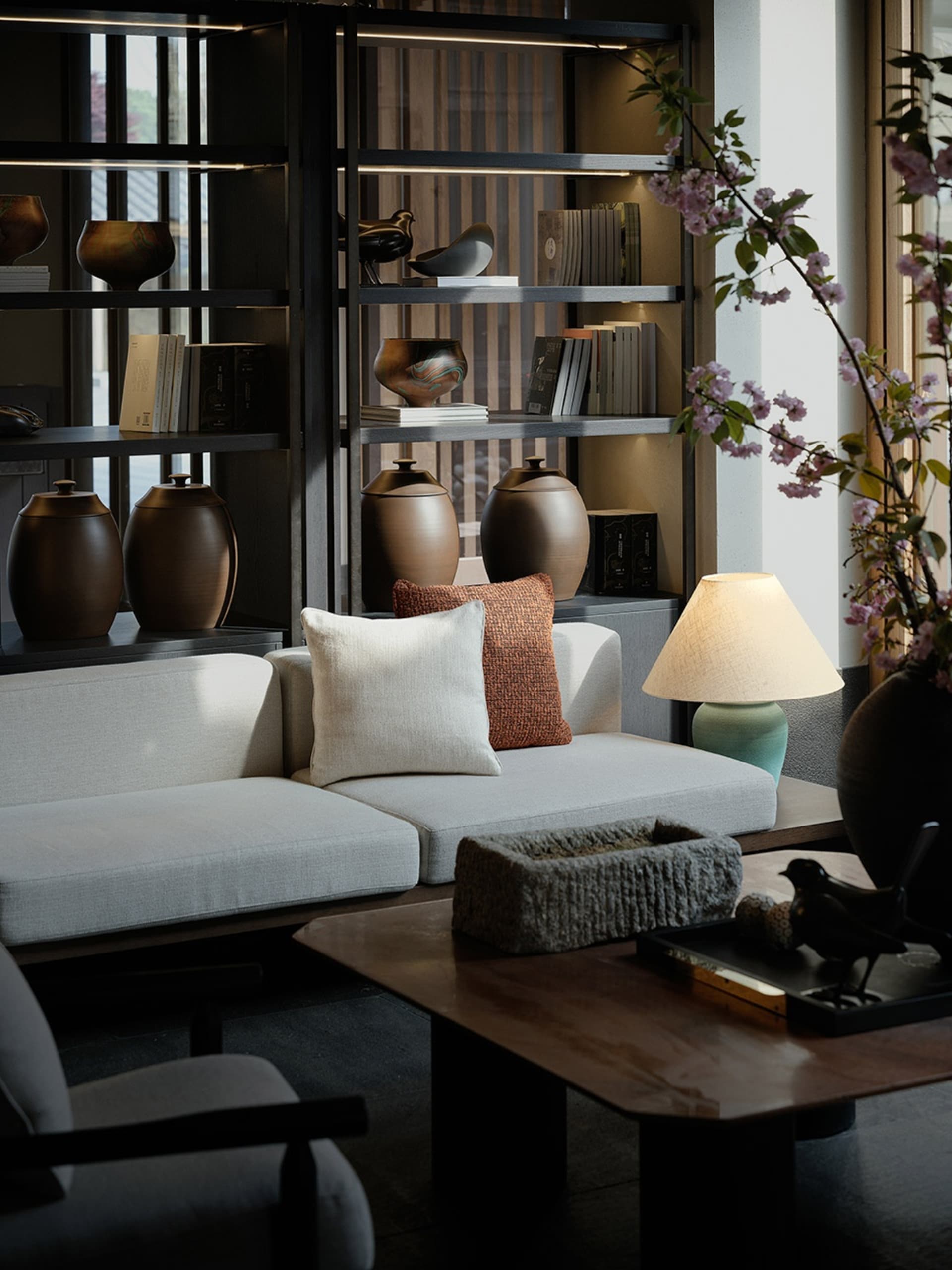 A modern living room with a white textured sofa adorned with pillows, a wooden coffee table with decorative objects, and a la