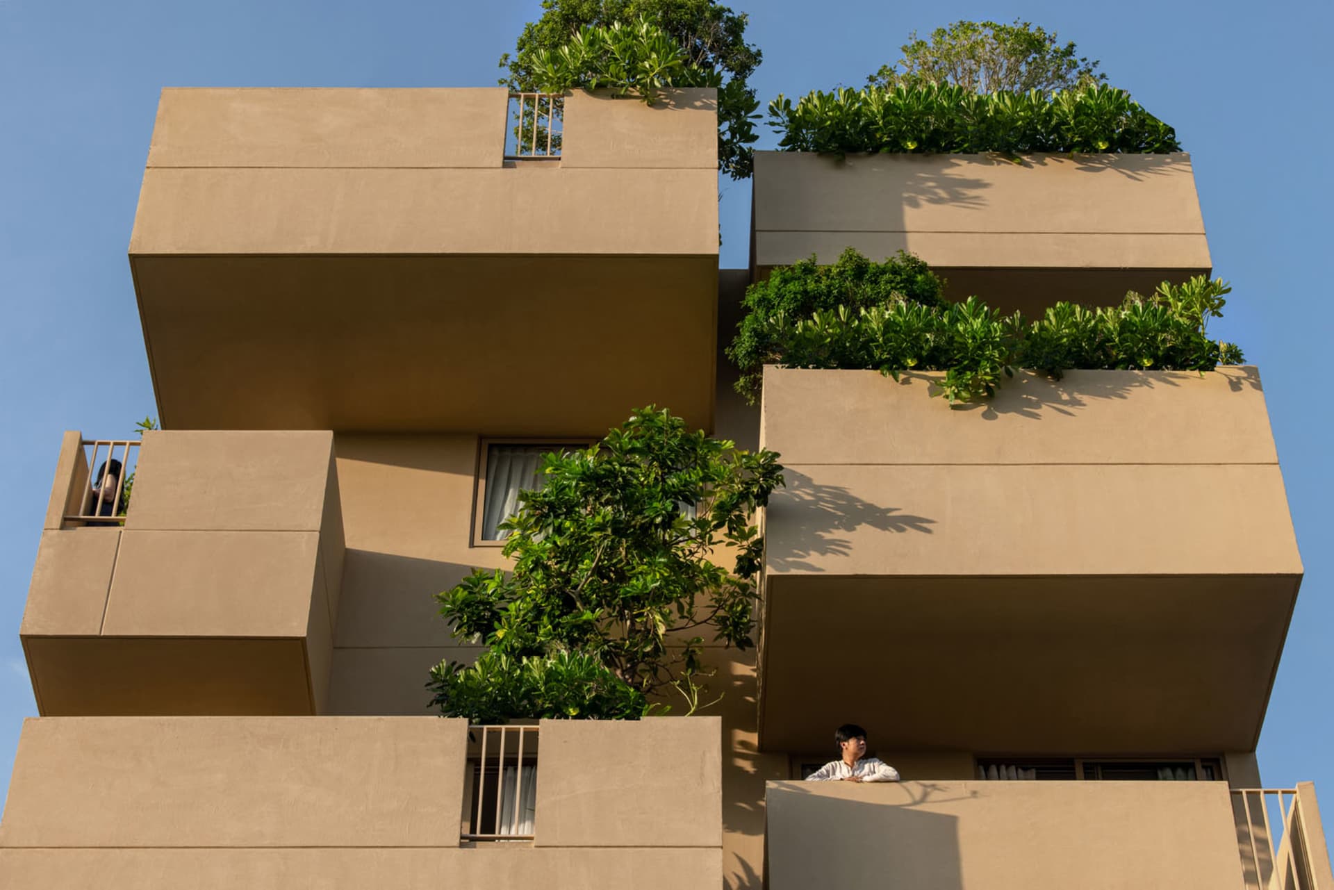 Modern residential building with concrete balconies and green plants.